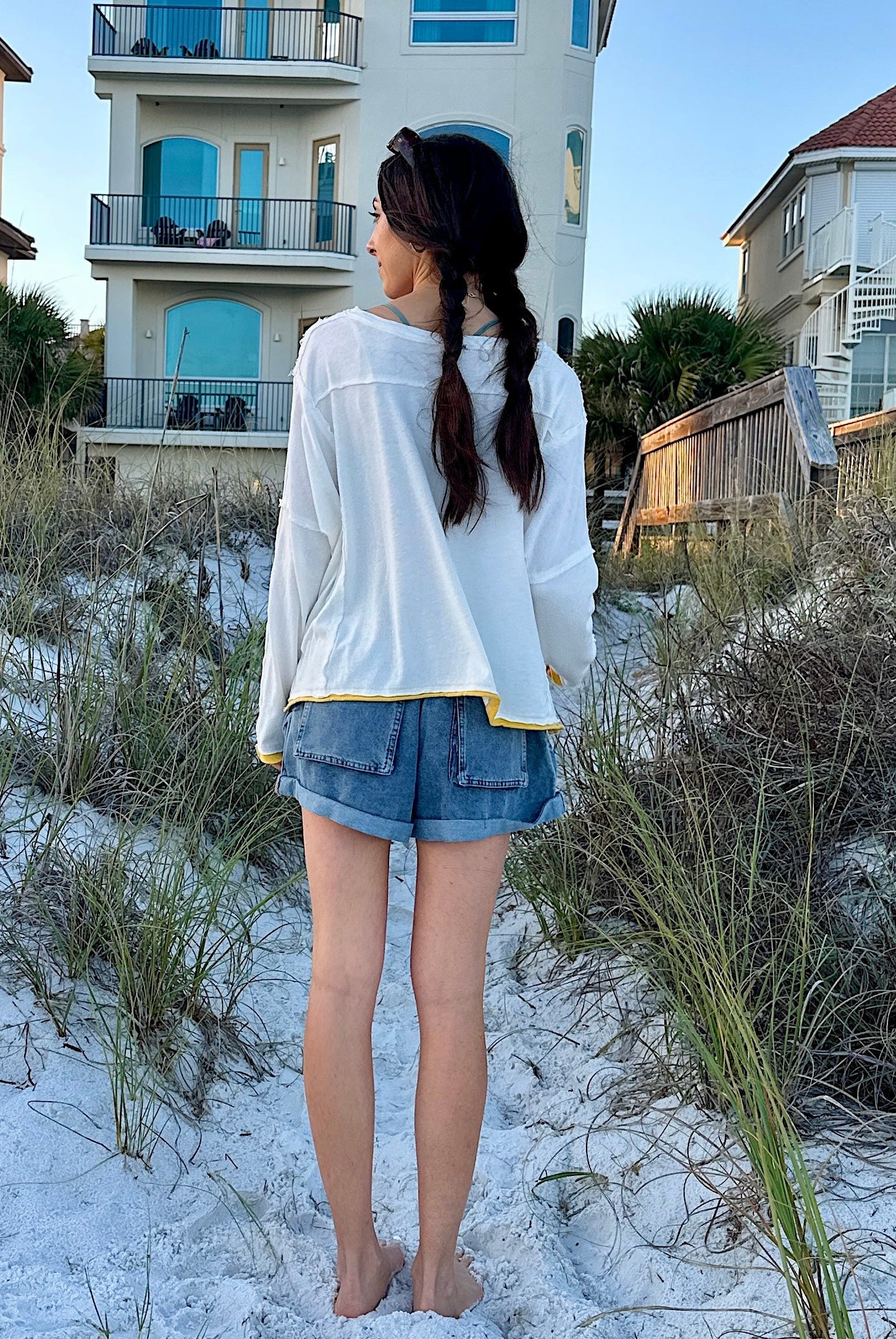 Woman standing on a sandy beach with houses in the background
