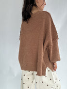 Person wearing a brown gingerbread man sweater with a white background to show solid back view