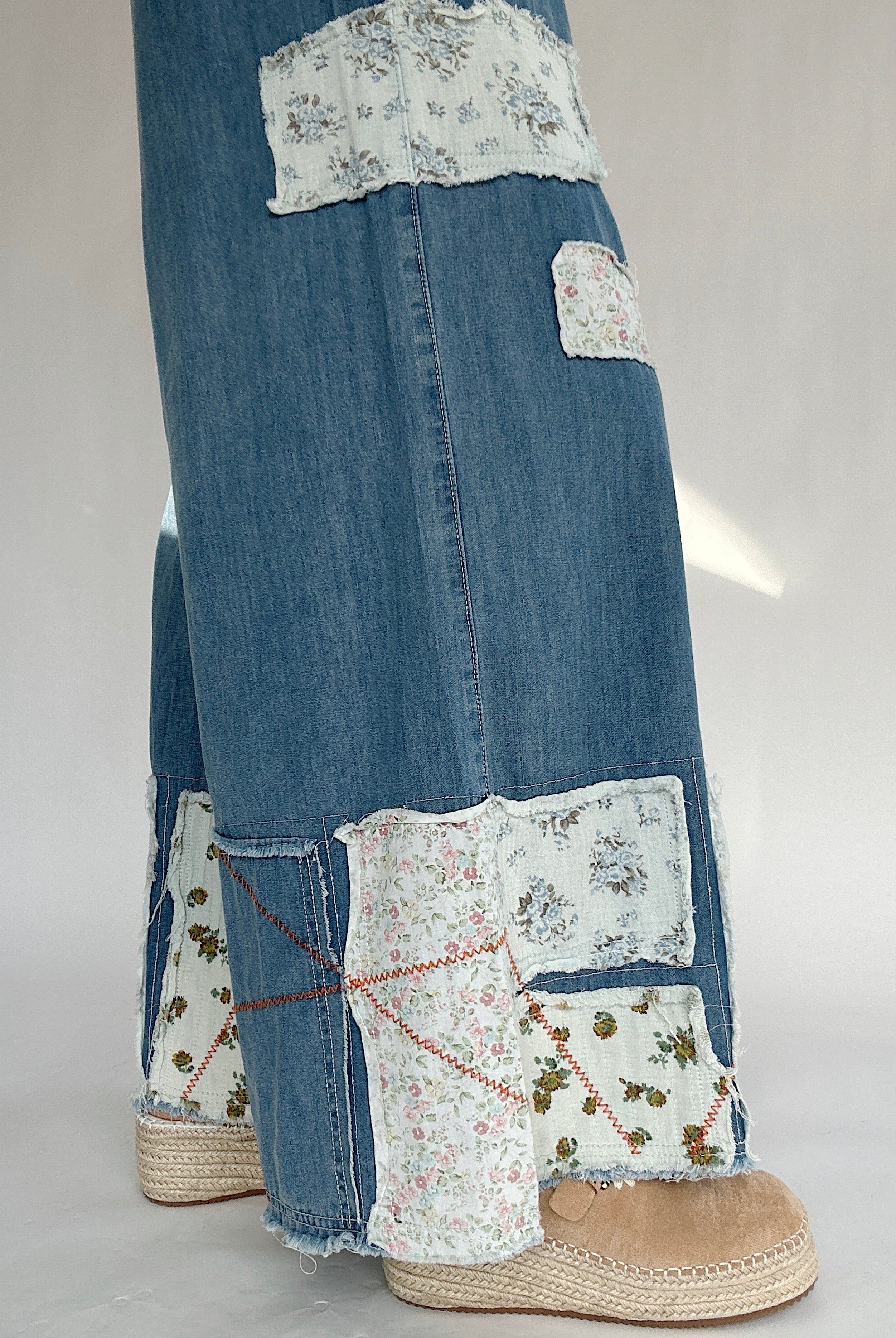 Blue jeans with floral patchwork on a white background to show the patch details