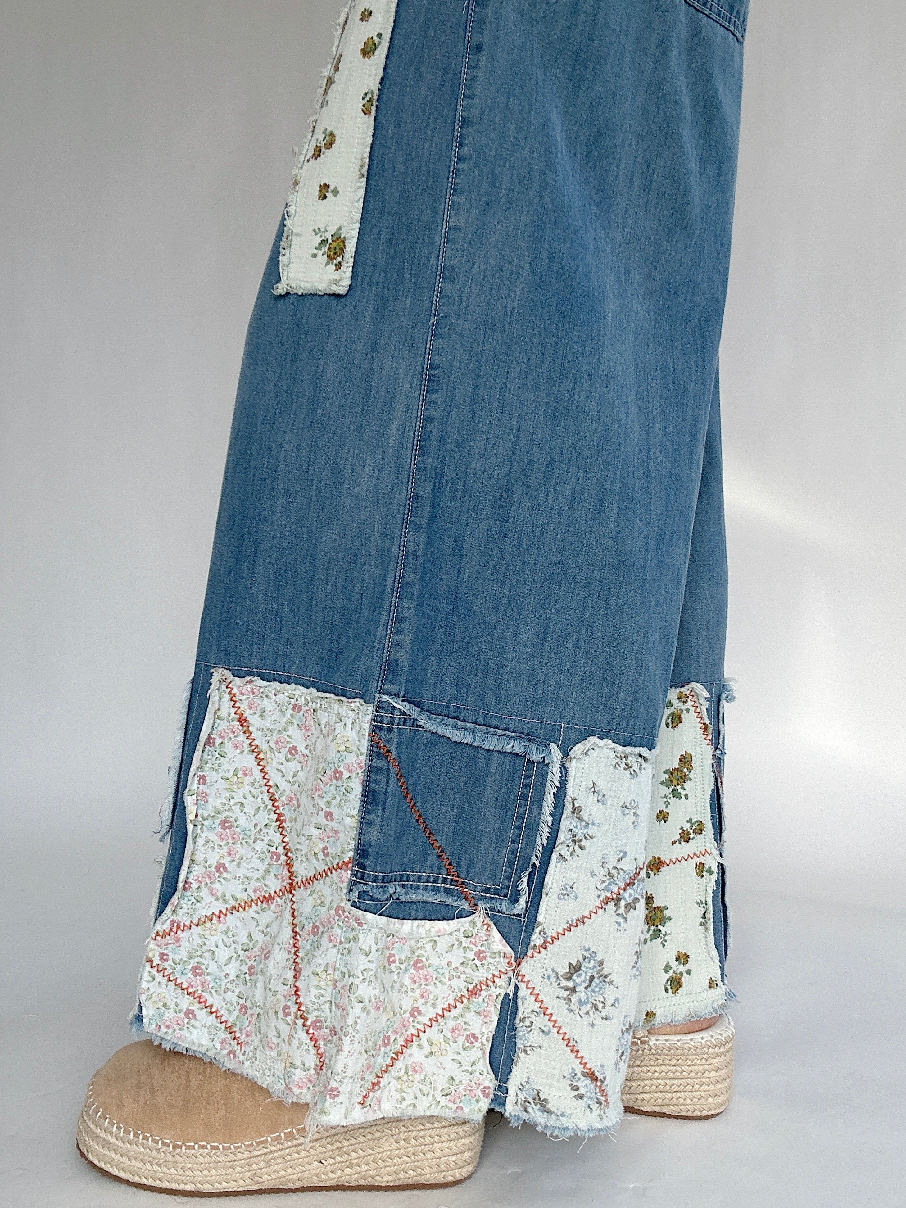 Denim pants with floral patchwork and espadrille clogs on a white gray background to show patchwork details