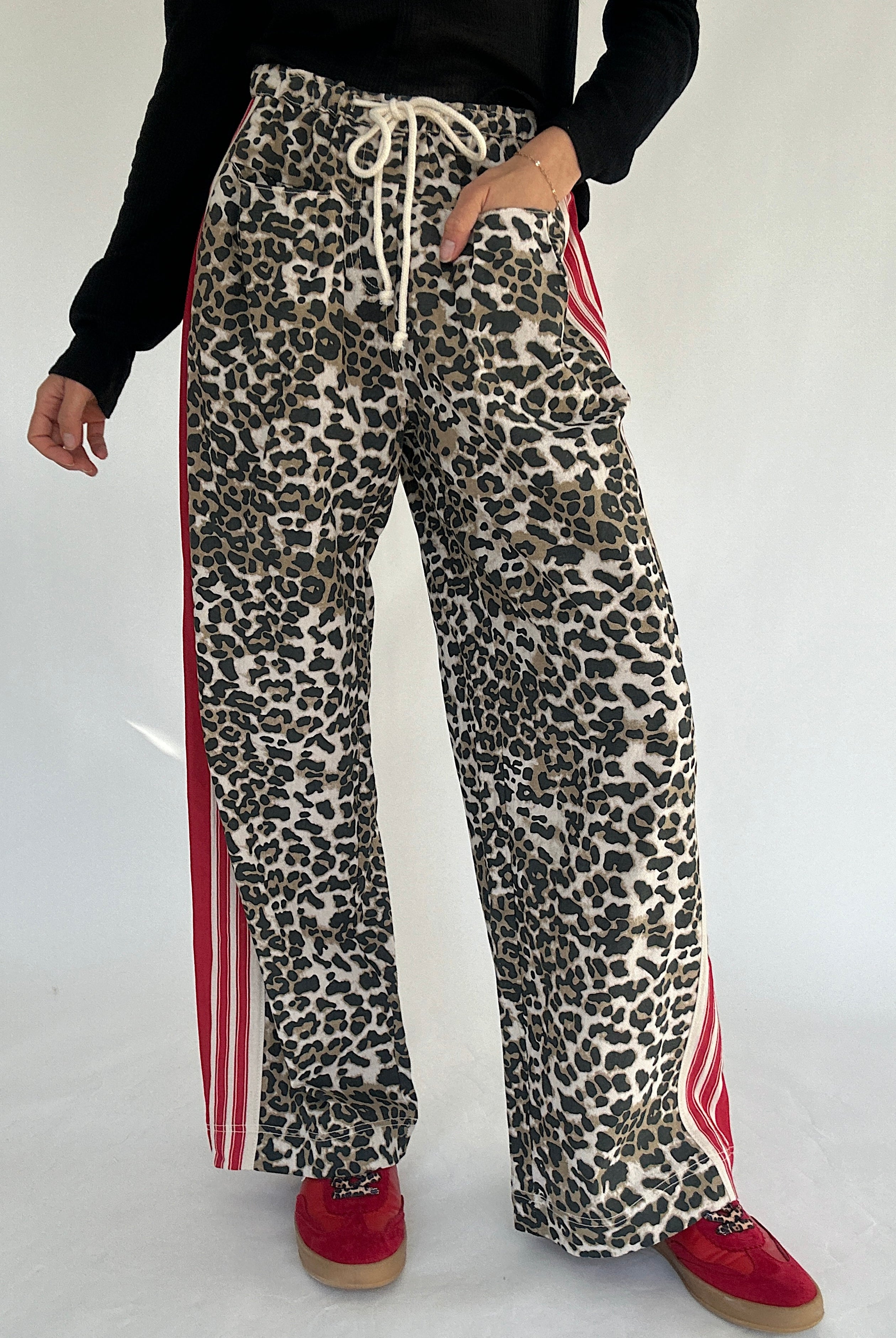 Leopard print pants with red stripes worn by a person on a white background