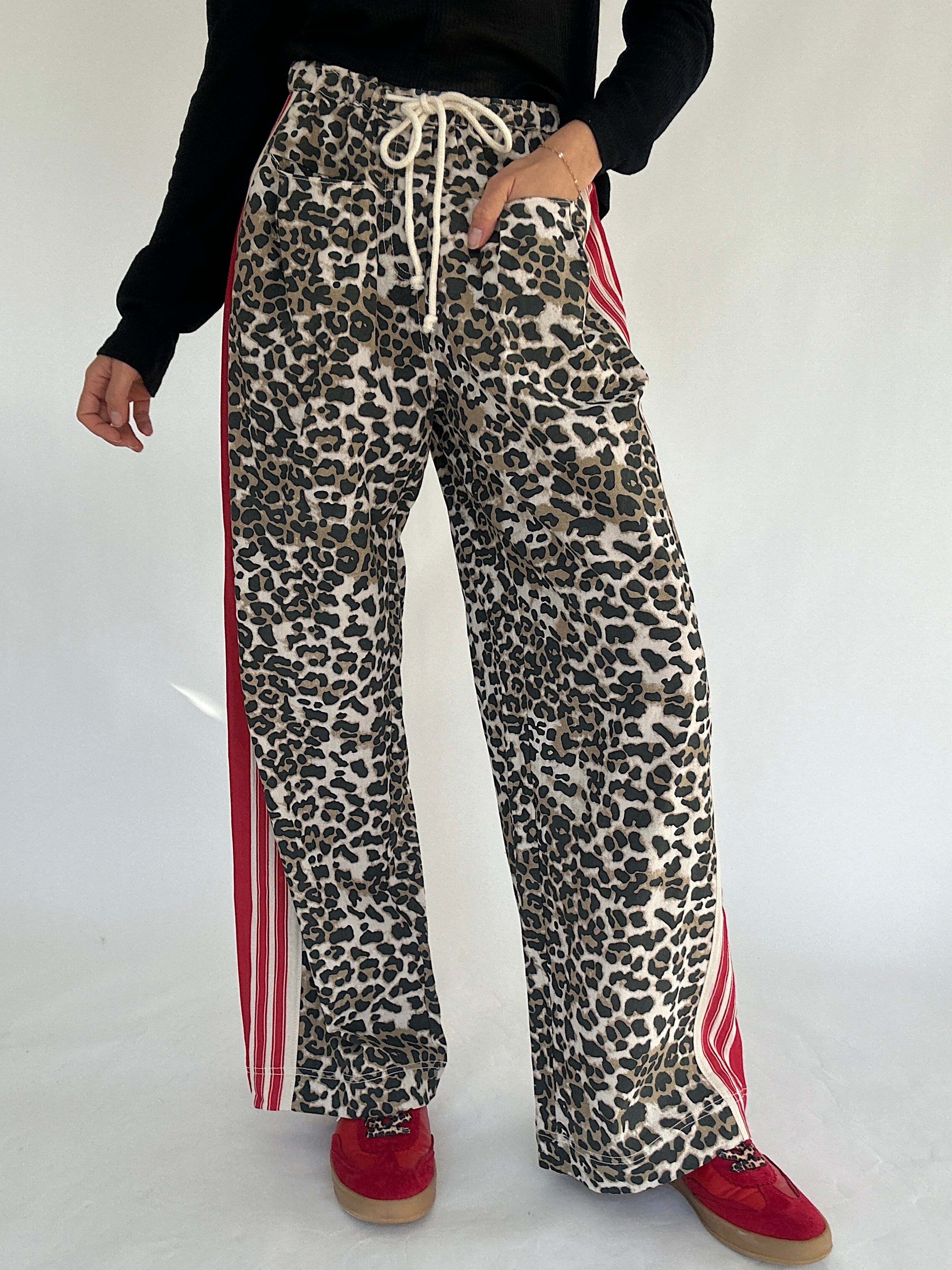 Leopard print pants with red stripes worn by a person on a white background