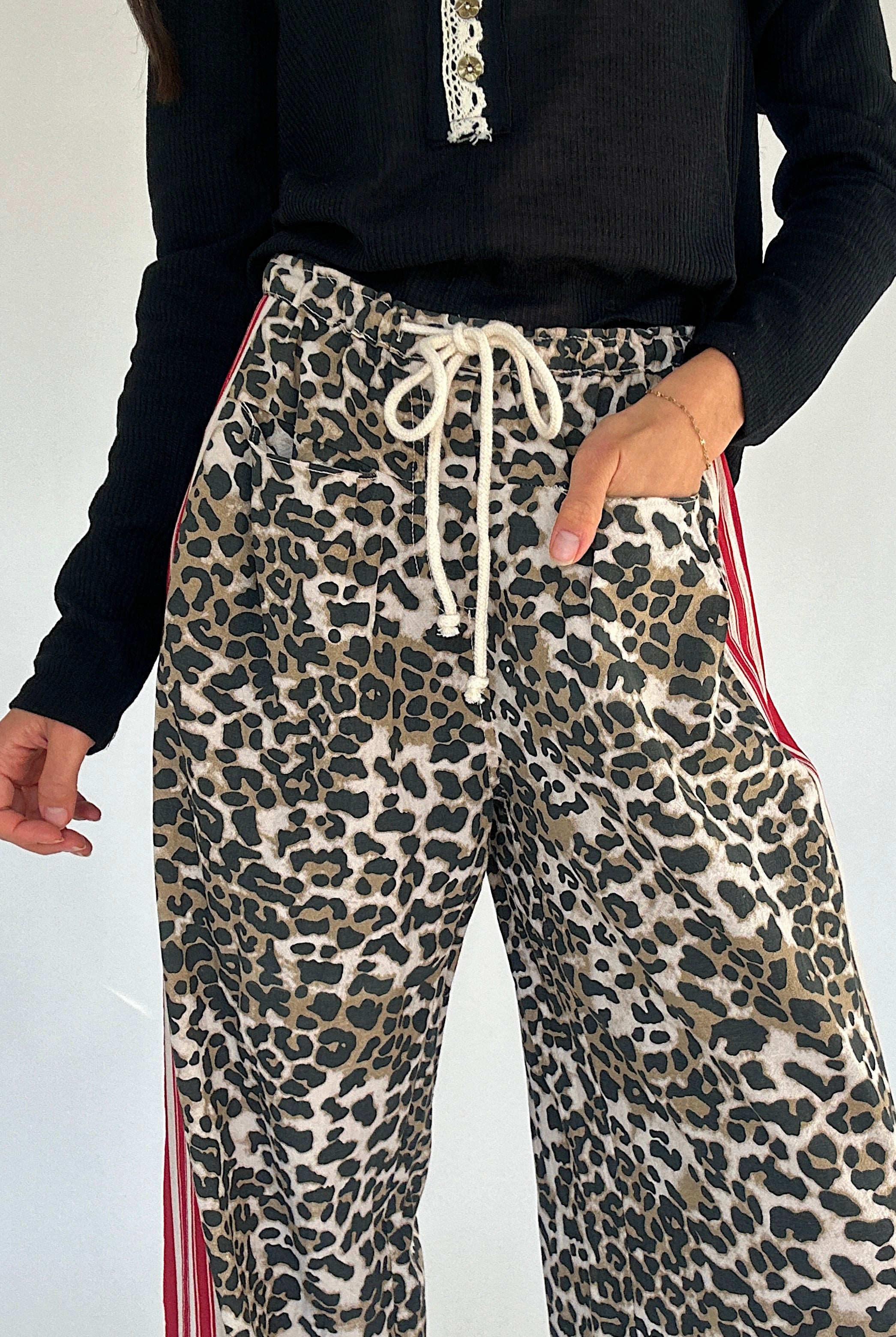 Leopard print pants with drawstring and red stripes on a plain background