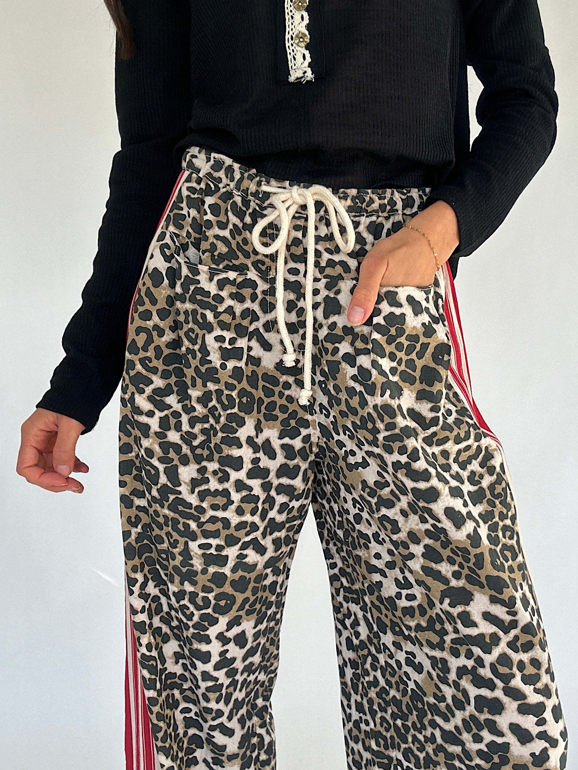 Leopard print pants with drawstring and red stripes on a plain background