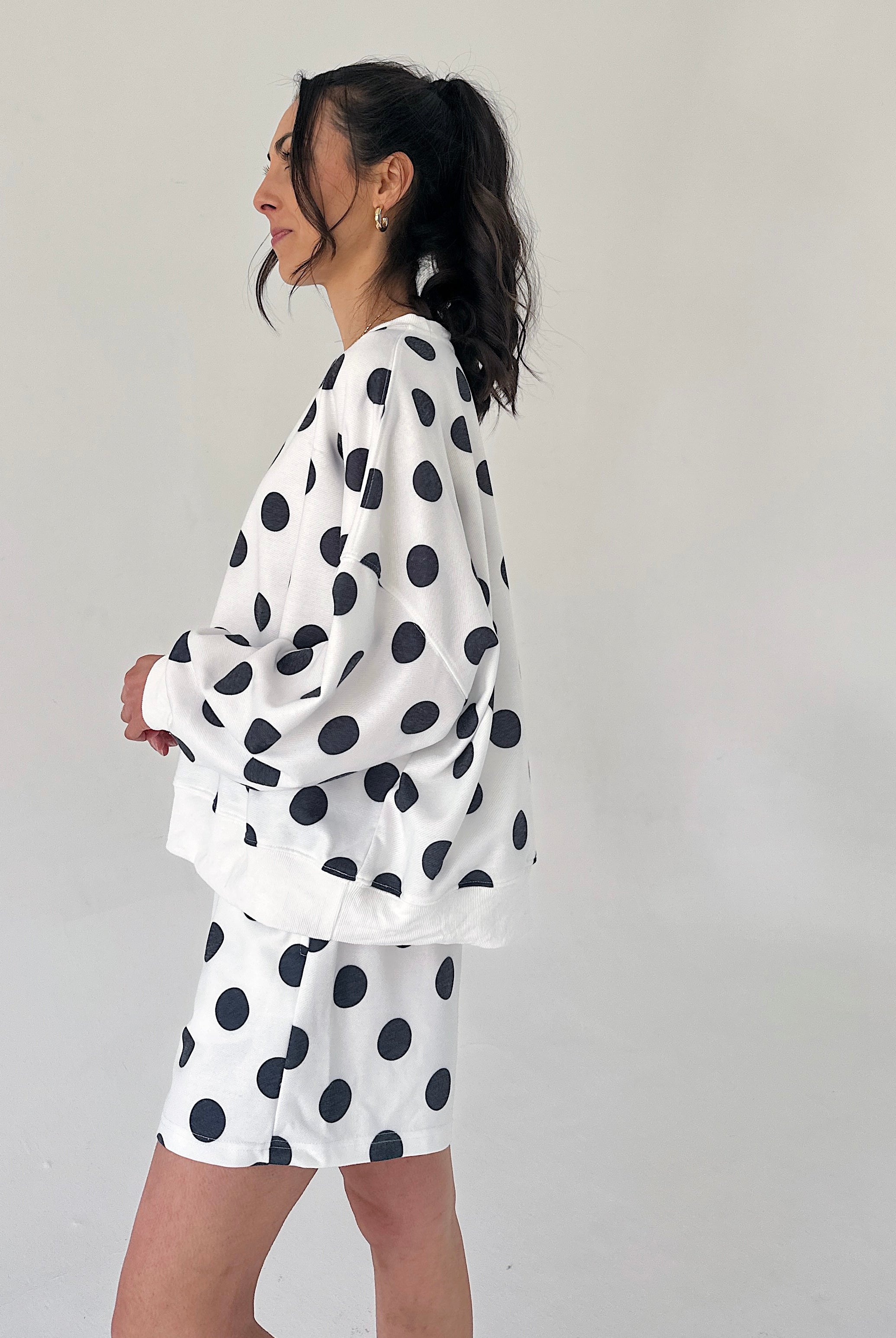 Person wearing a white outfit with black polka dots against a plain background