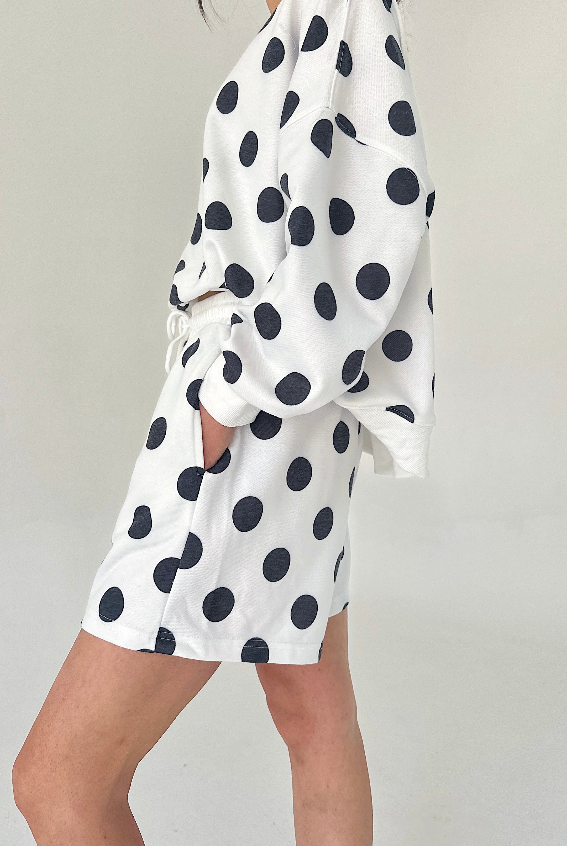 White dress with black polka dots on a plain background
