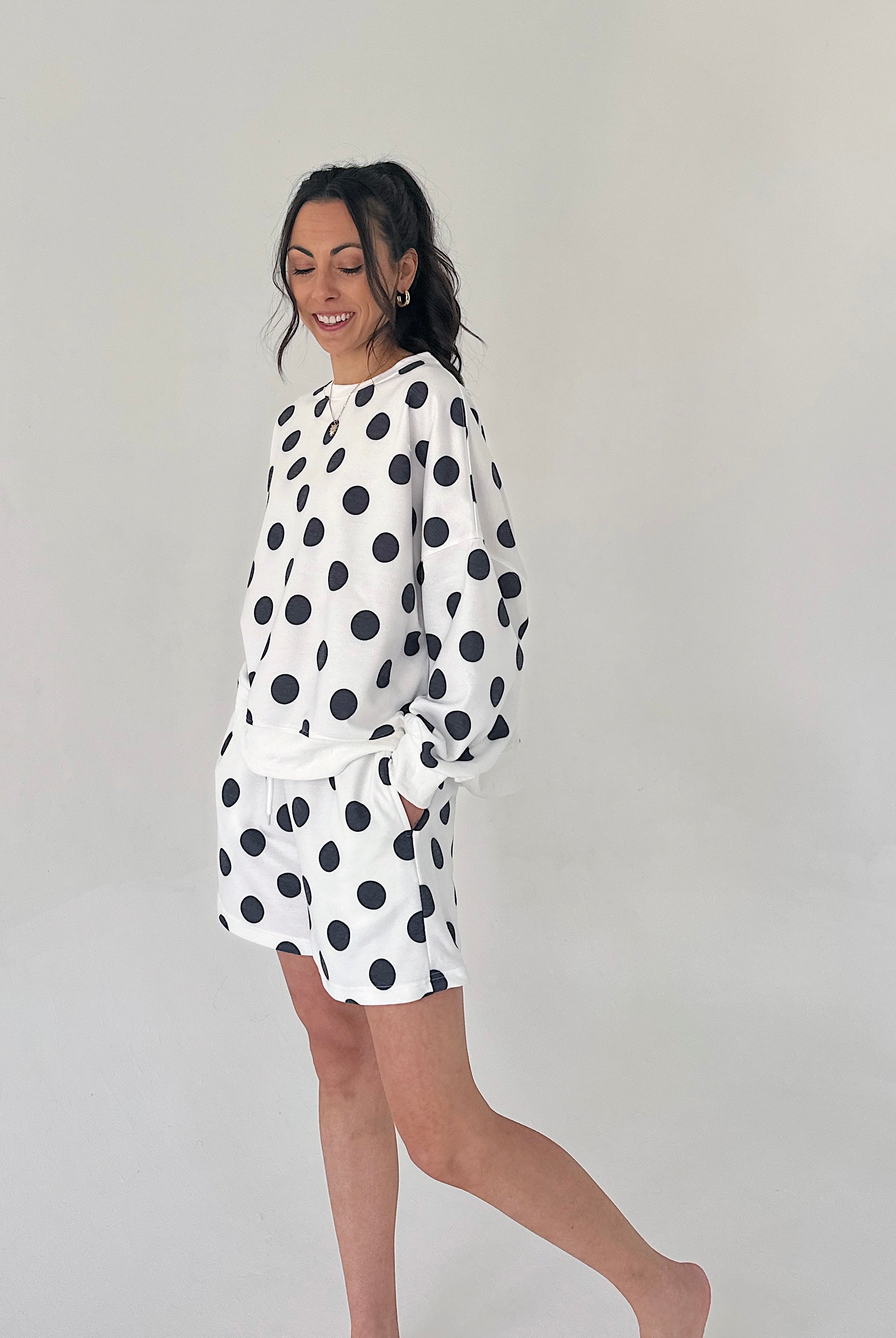 Woman wearing a white outfit with black polka dots on a plain background