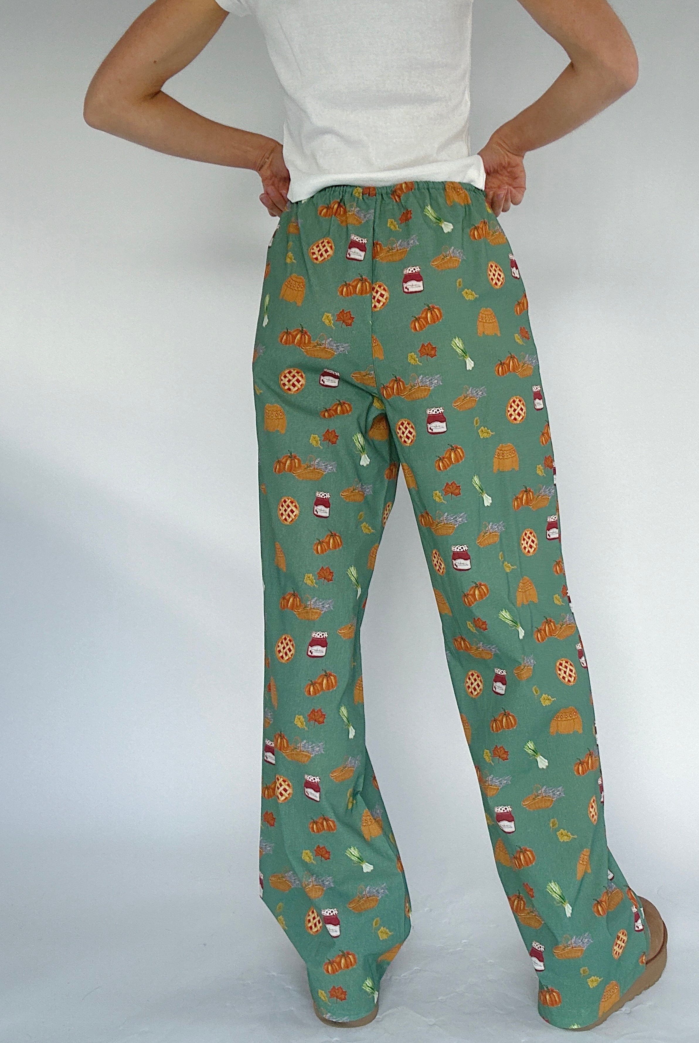Green fall patterned pants worn by a person on a white background showing back