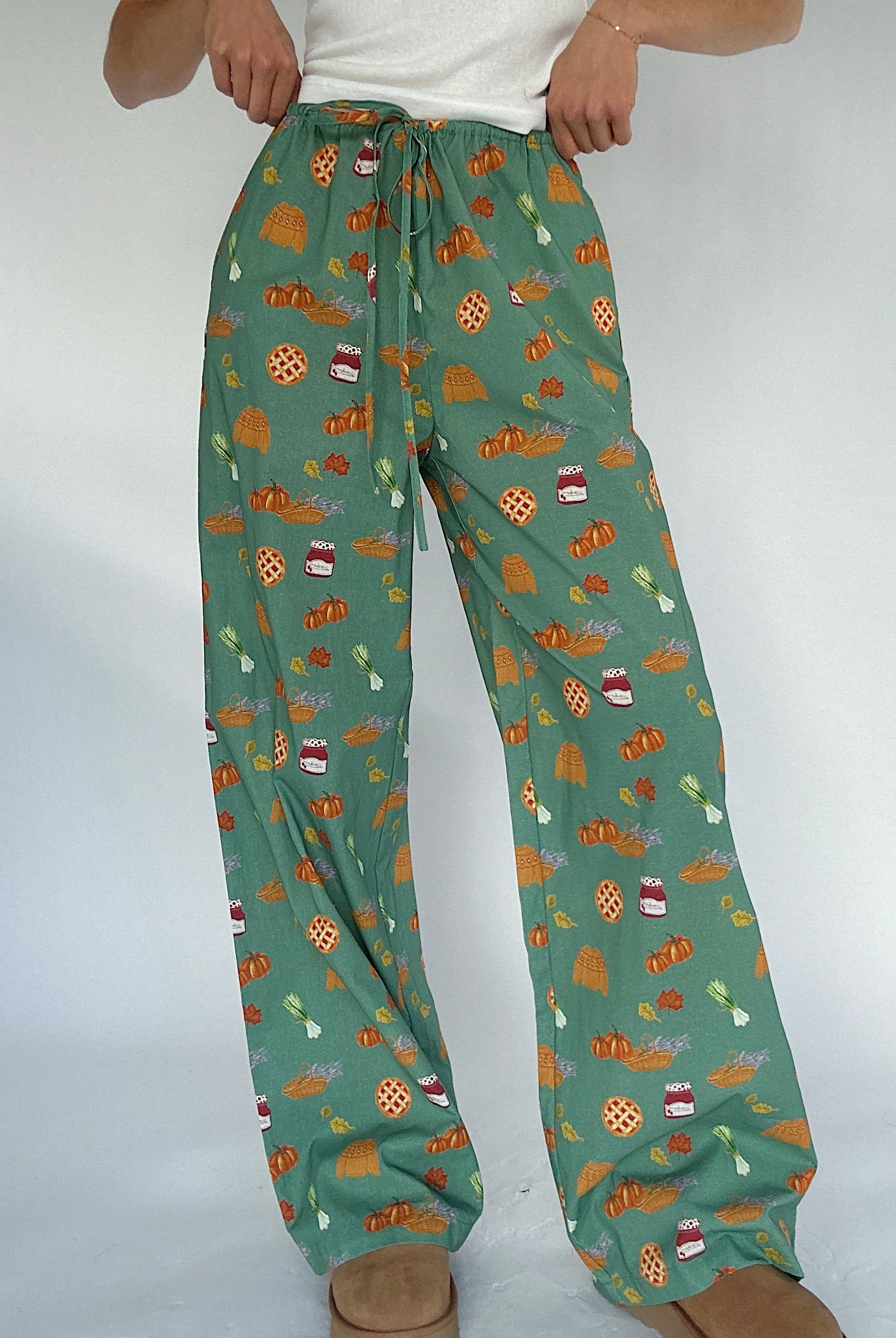 Green pants with autumn-themed pattern on a white background