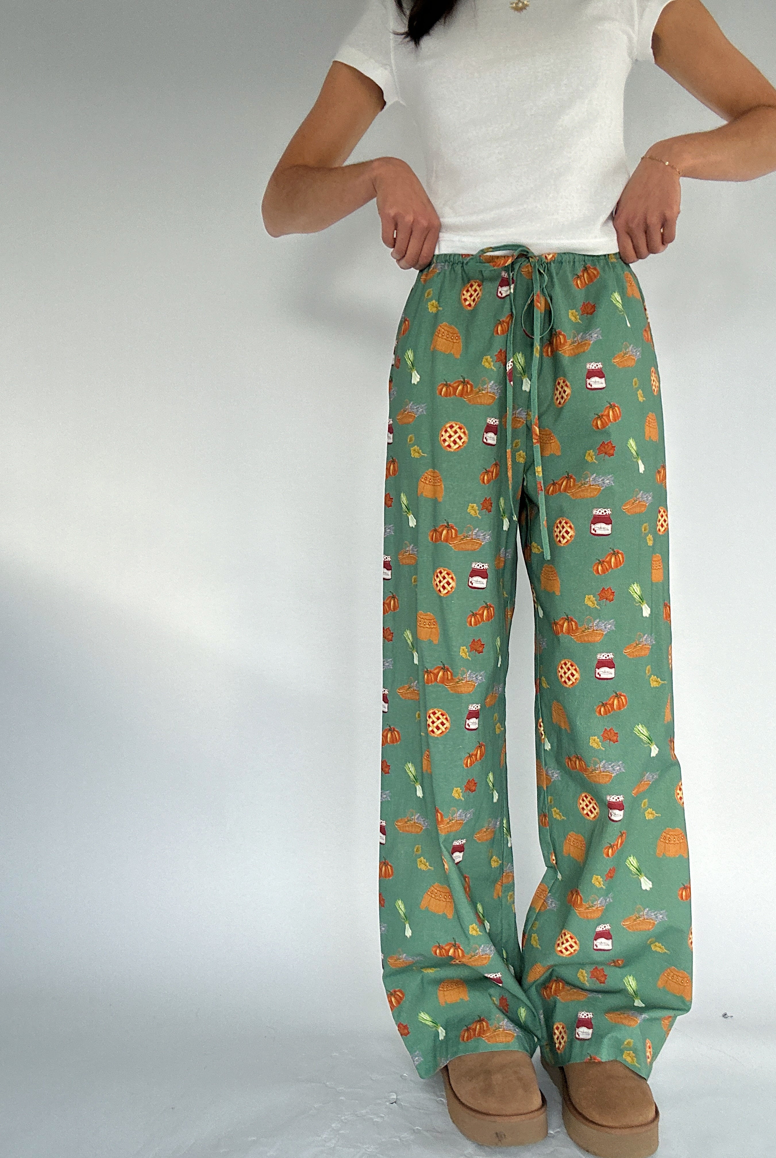 Person wearing green pants with fall inspired pattern on a white background