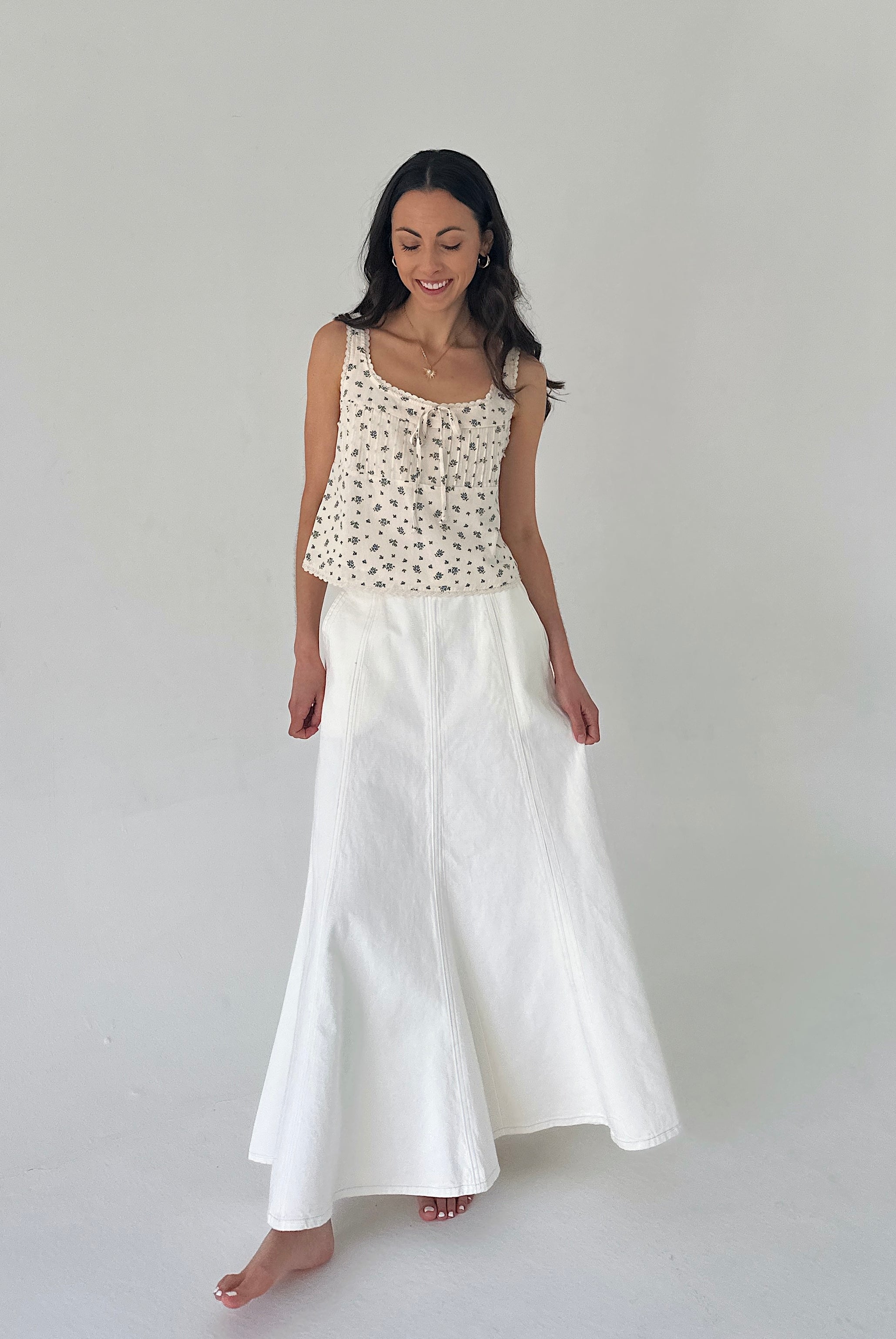 Woman wearing a floral top and white skirt on a plain background