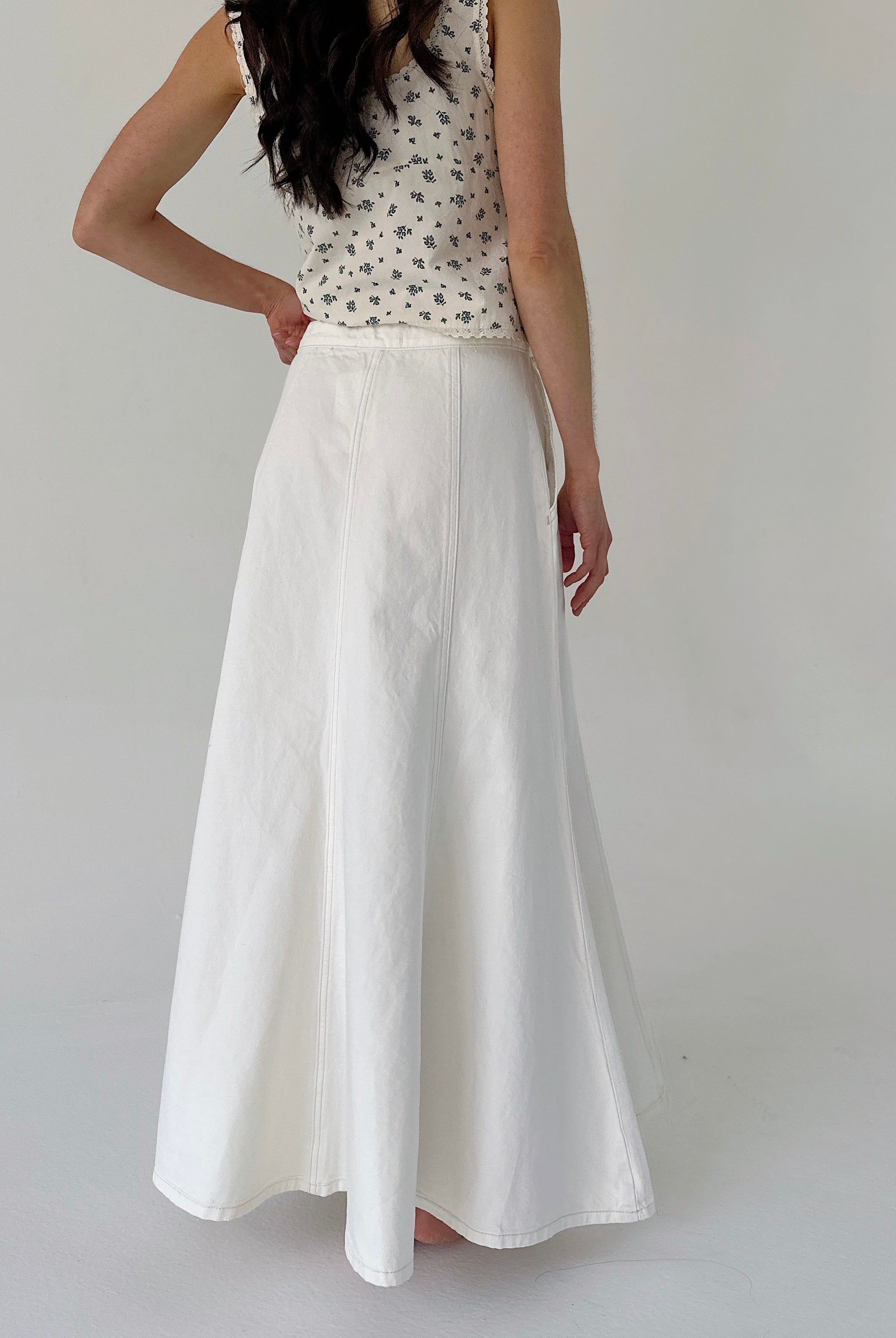 Person wearing a white skirt and patterned top on a plain background