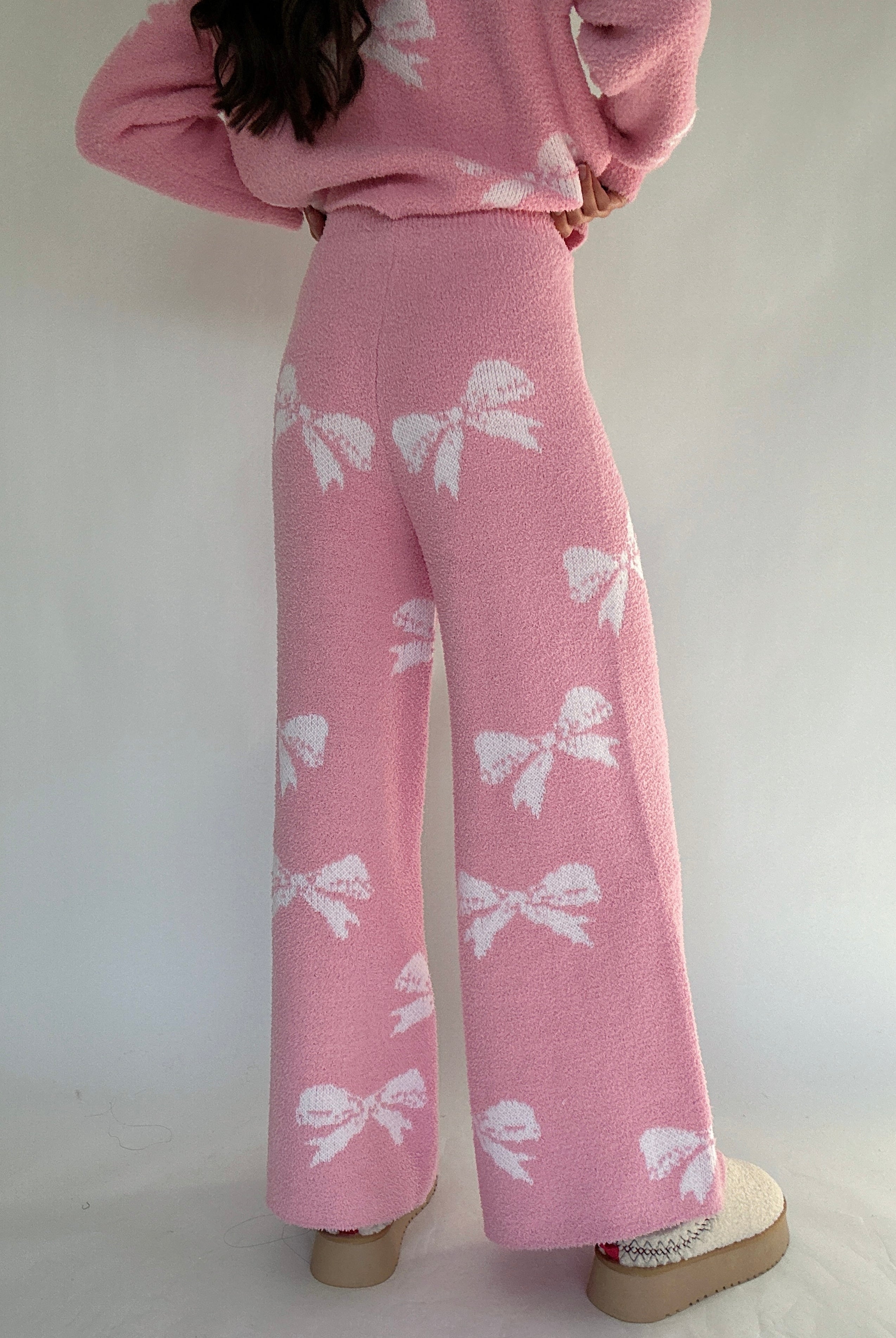 Person wearing a pink outfit with white bow patterns on a plain background showing back of pants