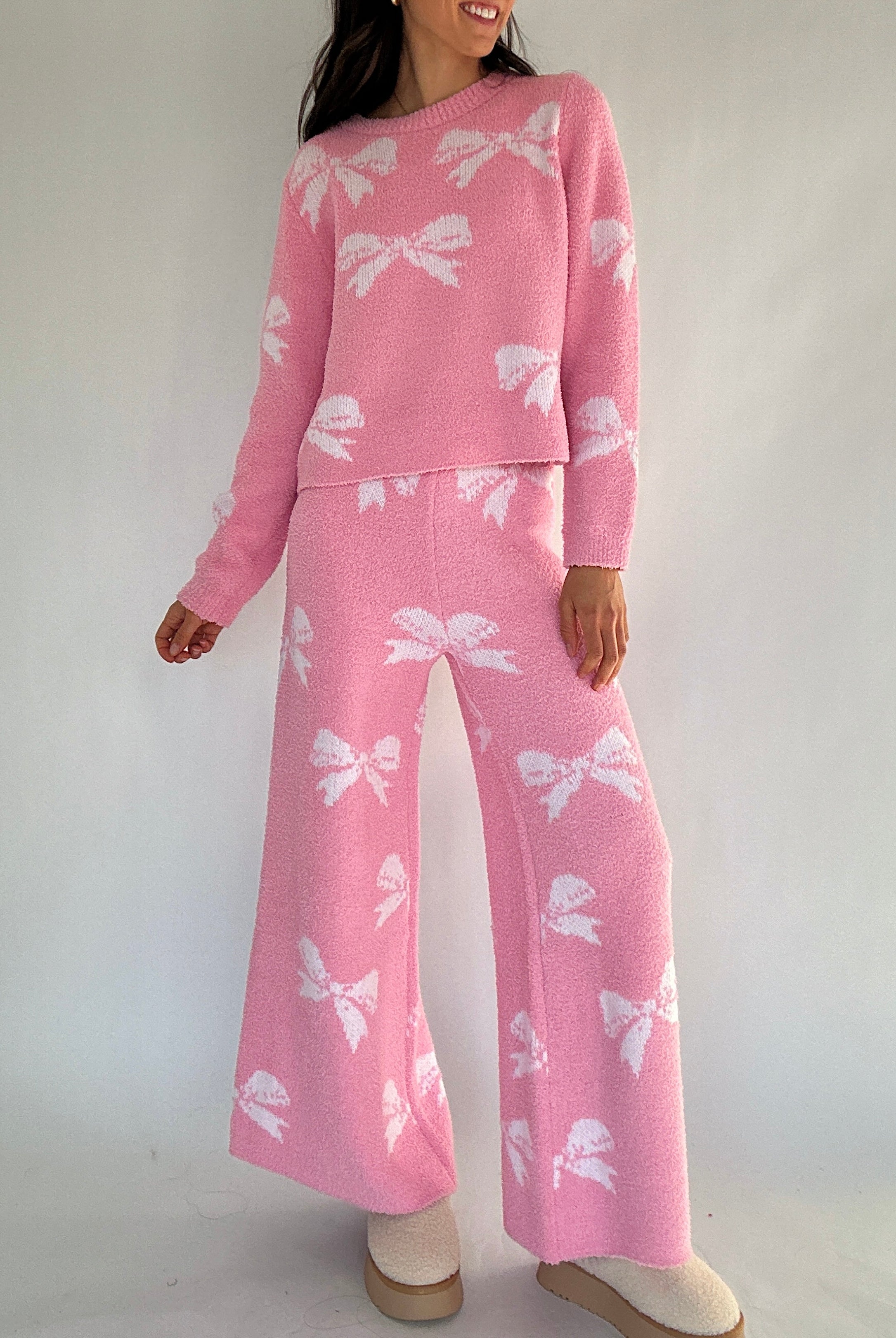 Person wearing a pink outfit with white bow patterns on a plain background