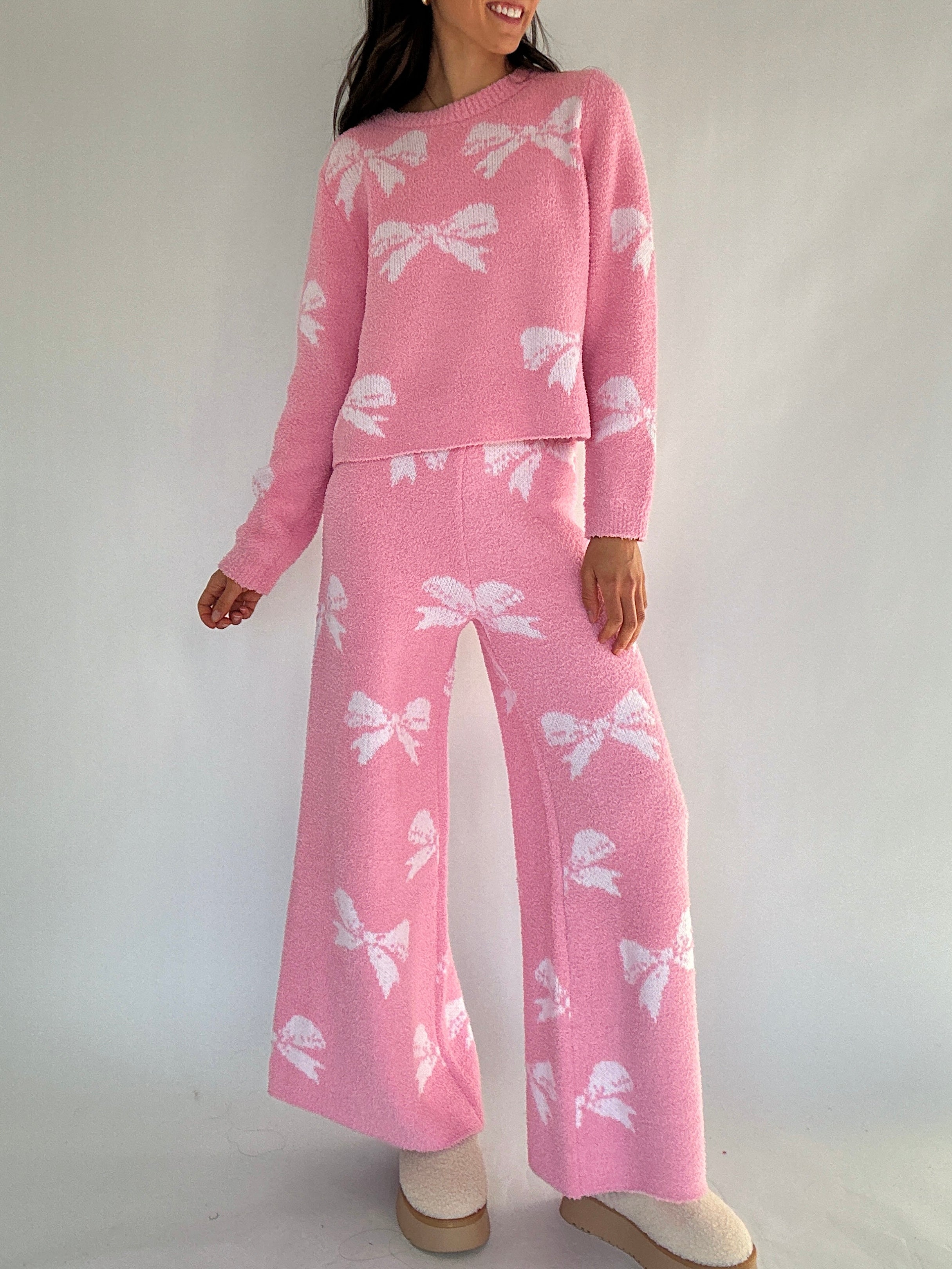 Person wearing a pink outfit with white bow patterns on a plain background