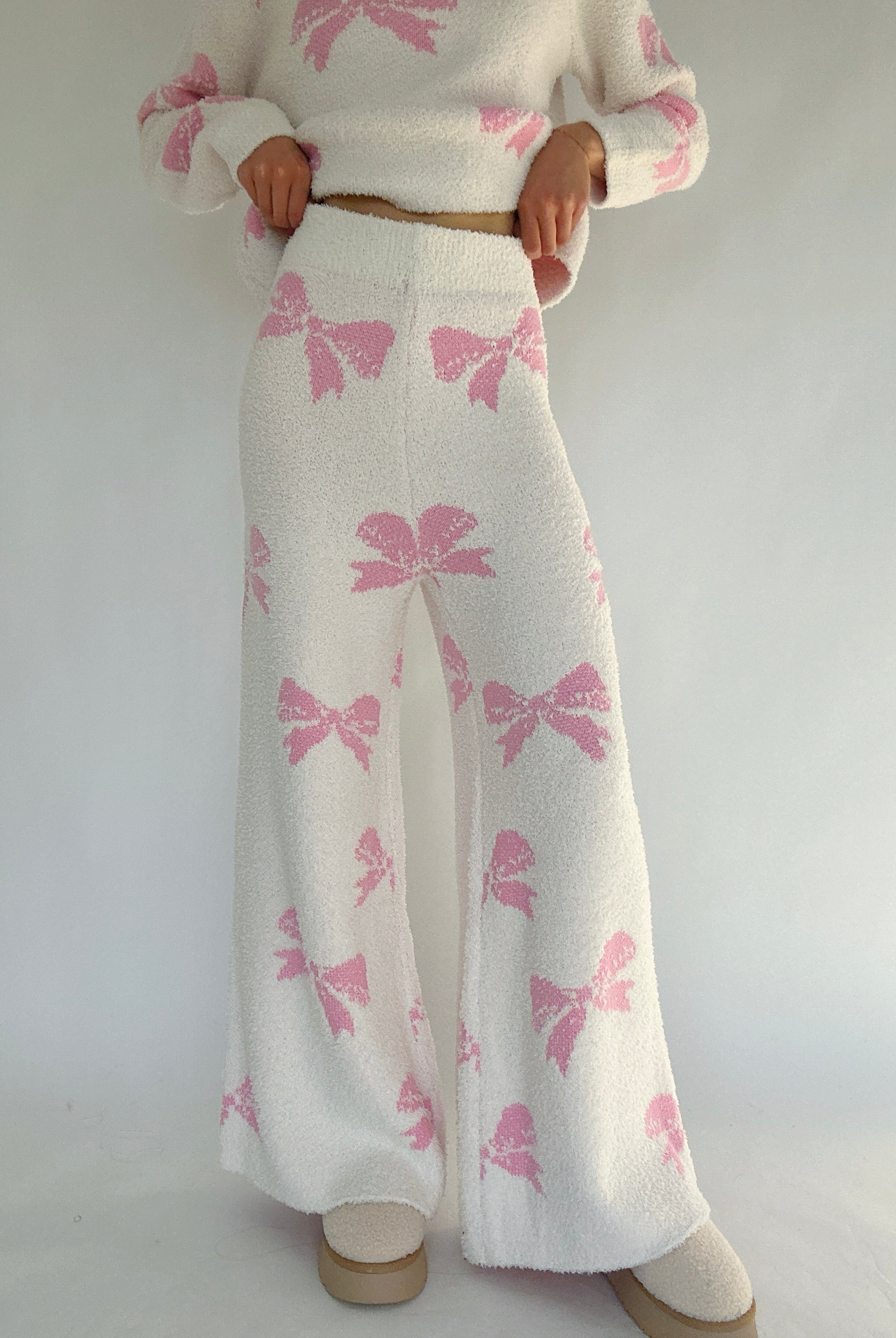 White outfit with pink bow pattern on a plain background showing front of pants