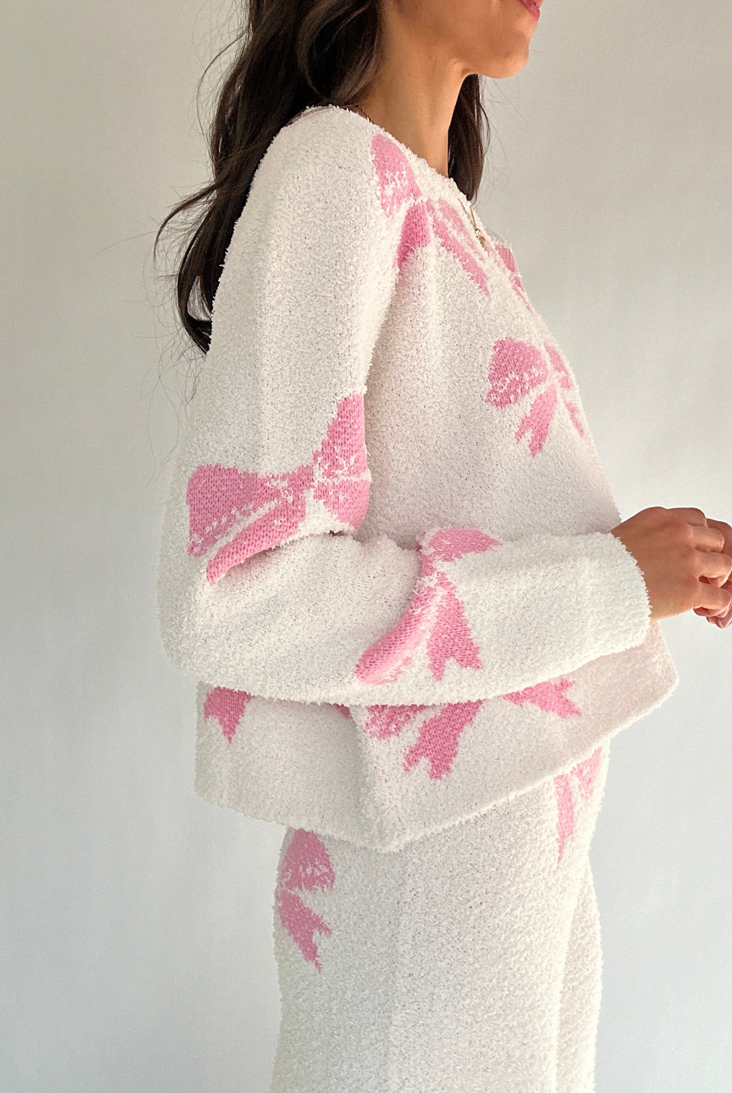 White outfit with pink bow patterns on a plain background side of top
