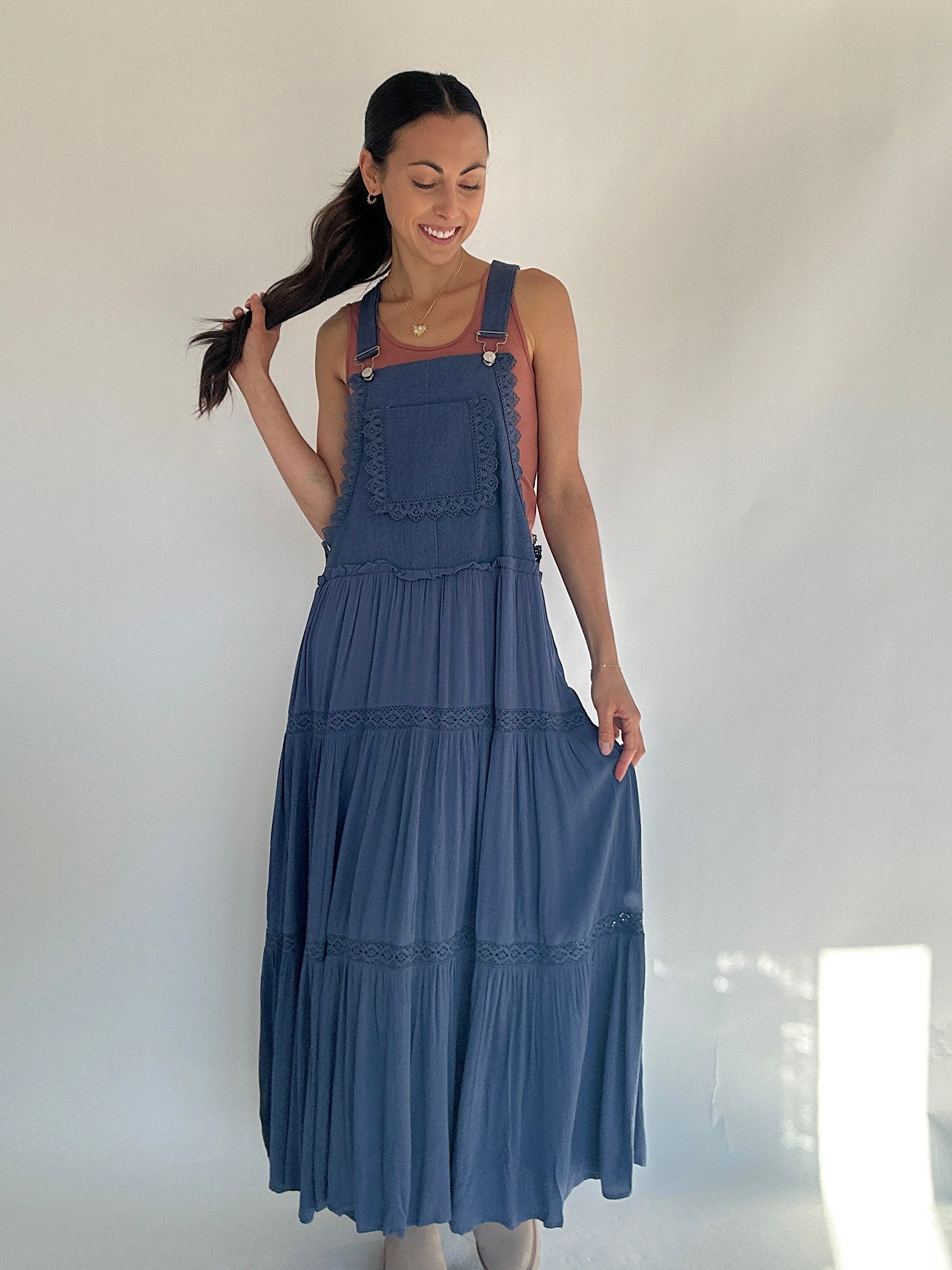 Woman wearing a blue overall dress against a white background