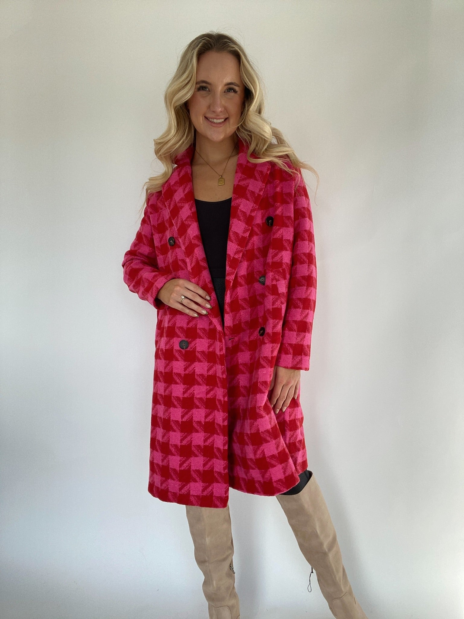 Woman wearing a pink and red houndstooth coat with boots