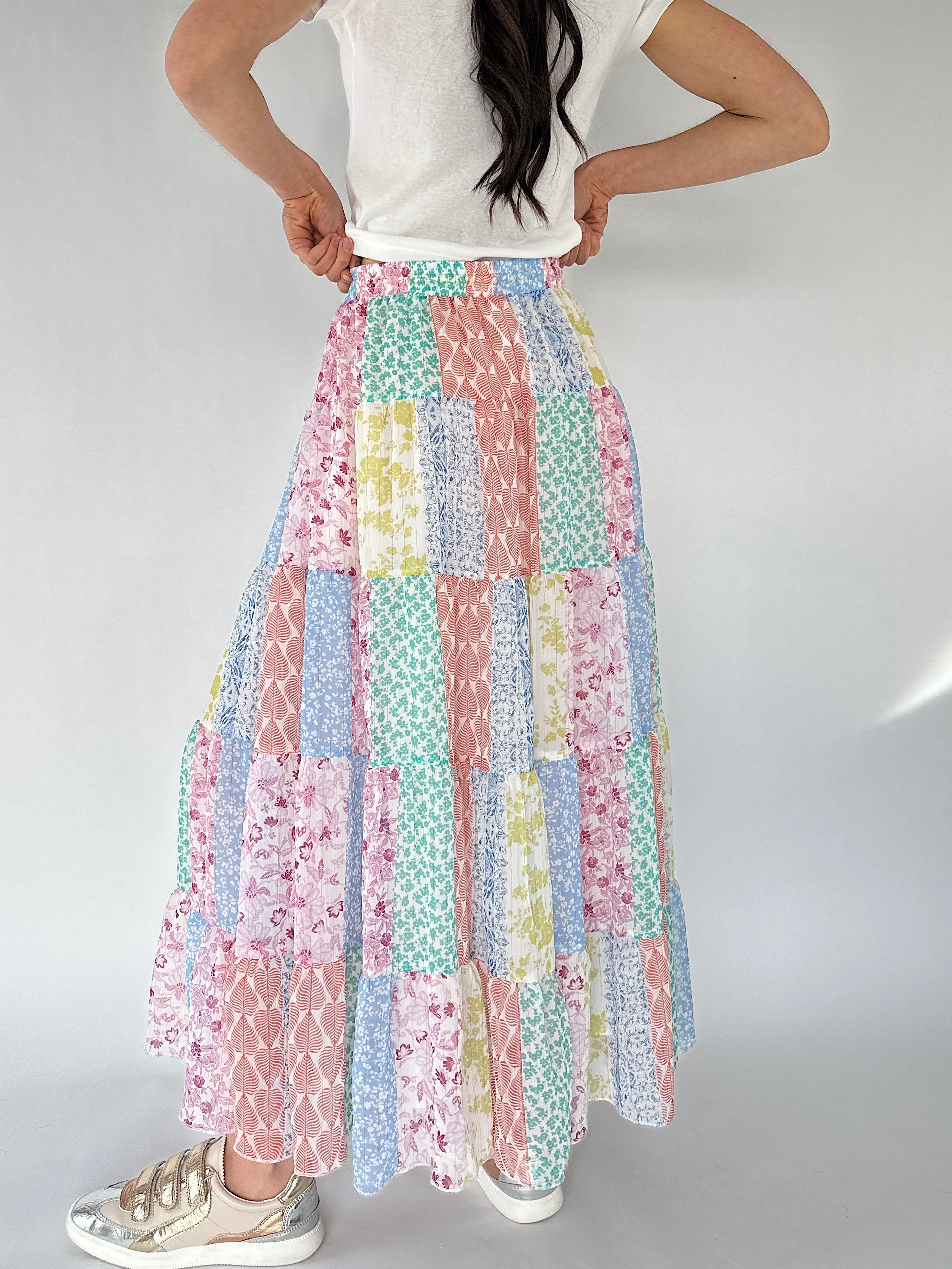 Person wearing a colorful patchwork skirt on a plain background from back