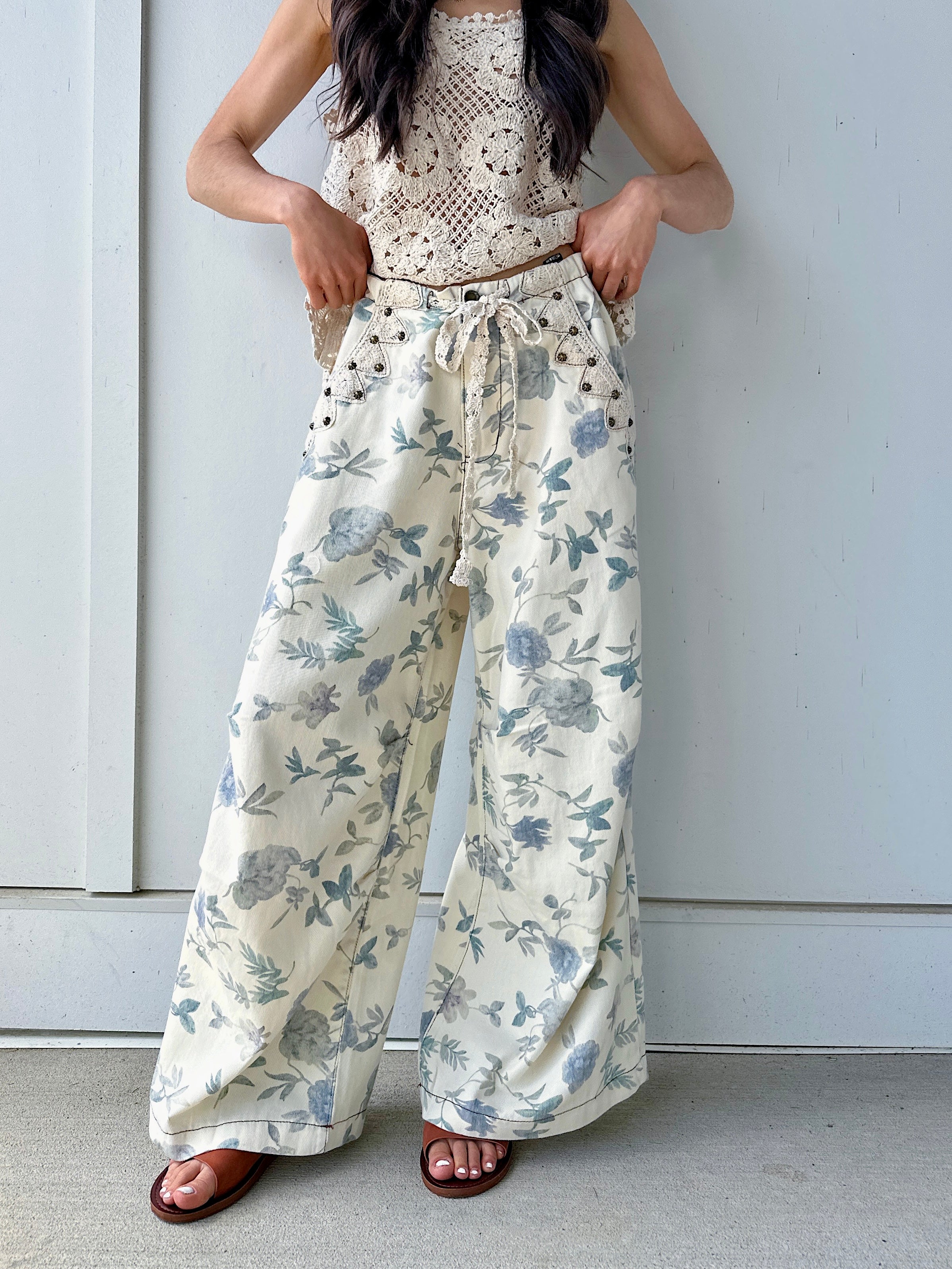 Person wearing cream and blue floral wide leg pants against a plain background