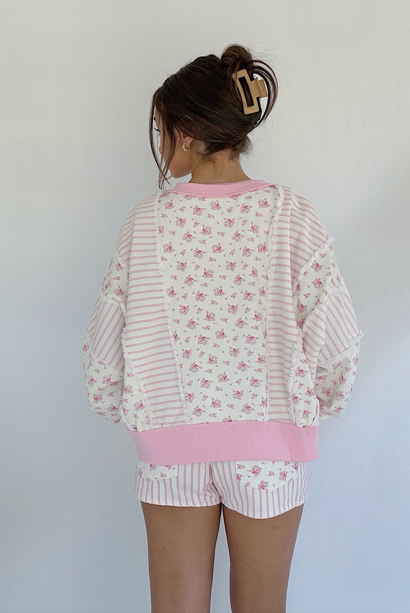 Person wearing a pink and white floral pajama set against a plain background in back