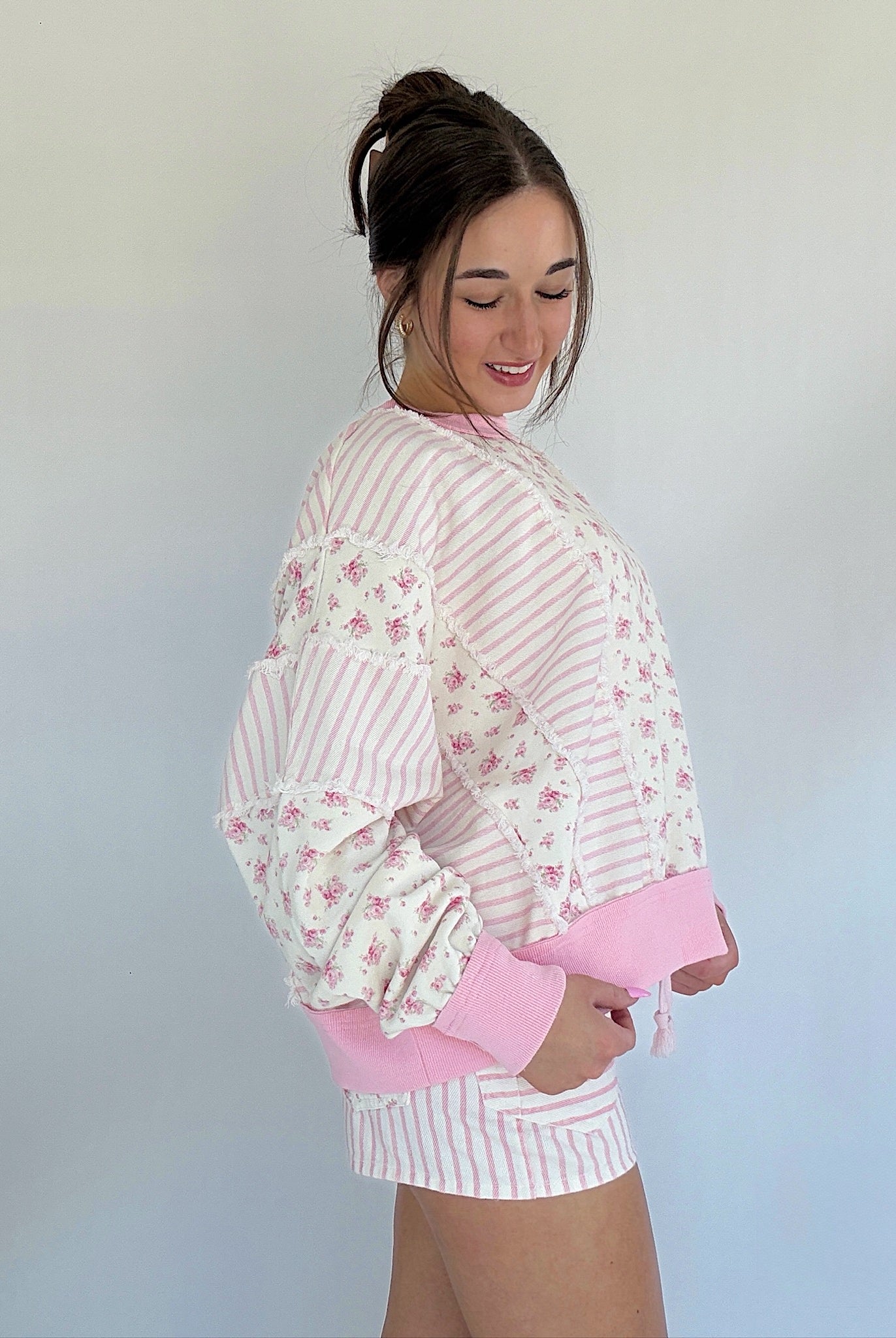 Woman wearing a pink and white striped outfit with floral details against a plain background