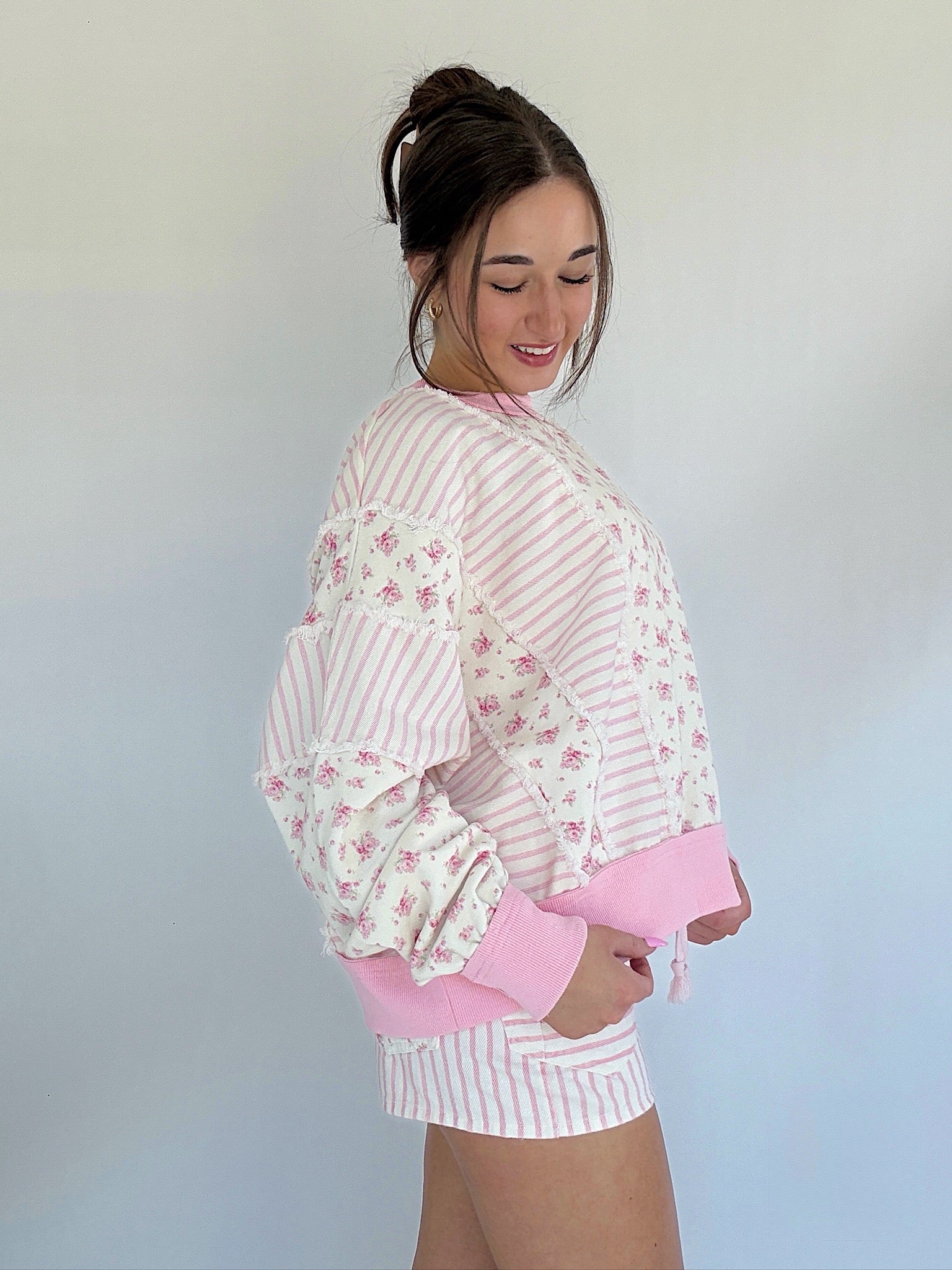 Woman wearing a pink and white striped outfit with floral details against a plain background