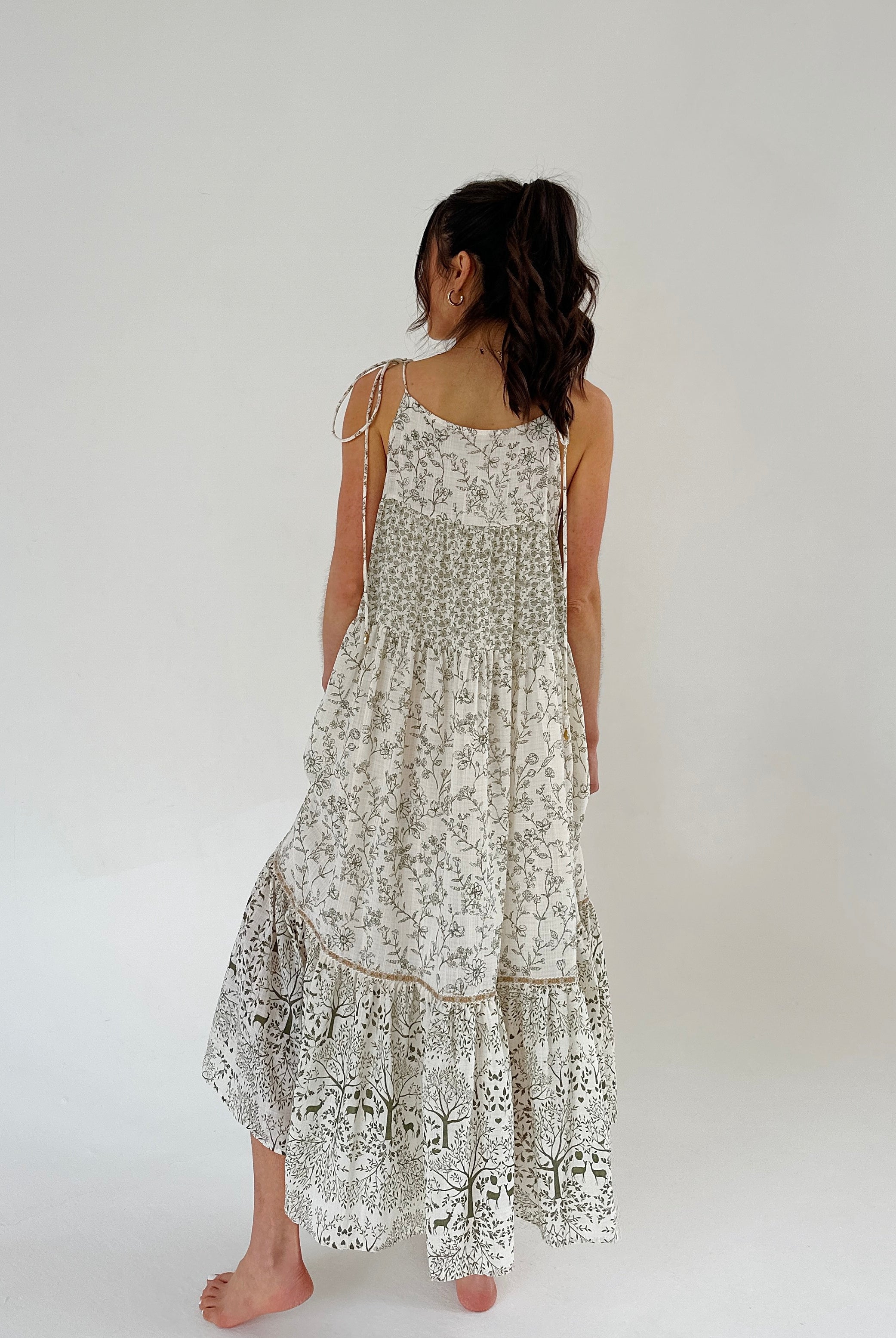 Woman wearing a floral dress on a plain background from back