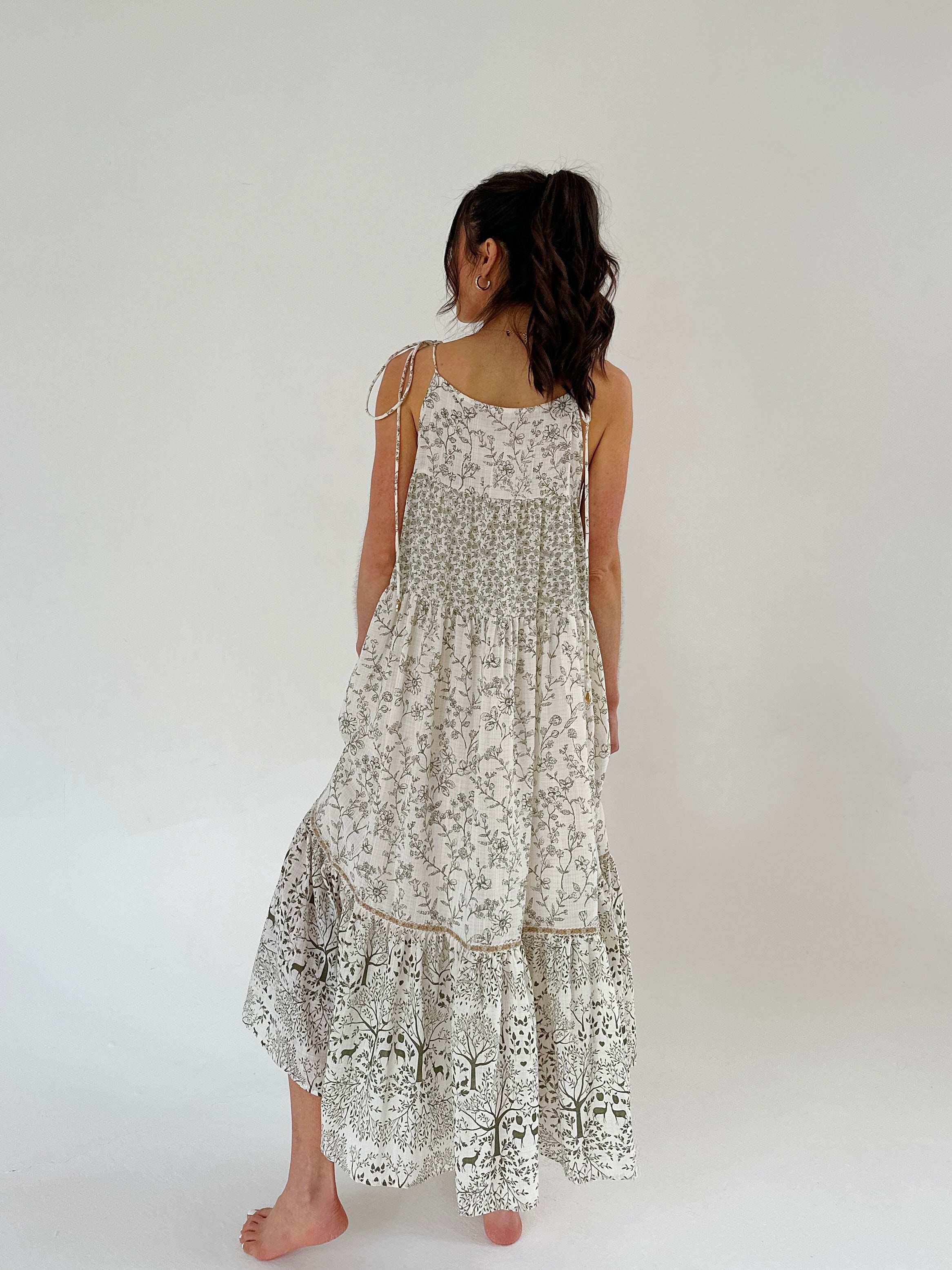 Woman wearing a floral dress on a plain background from back