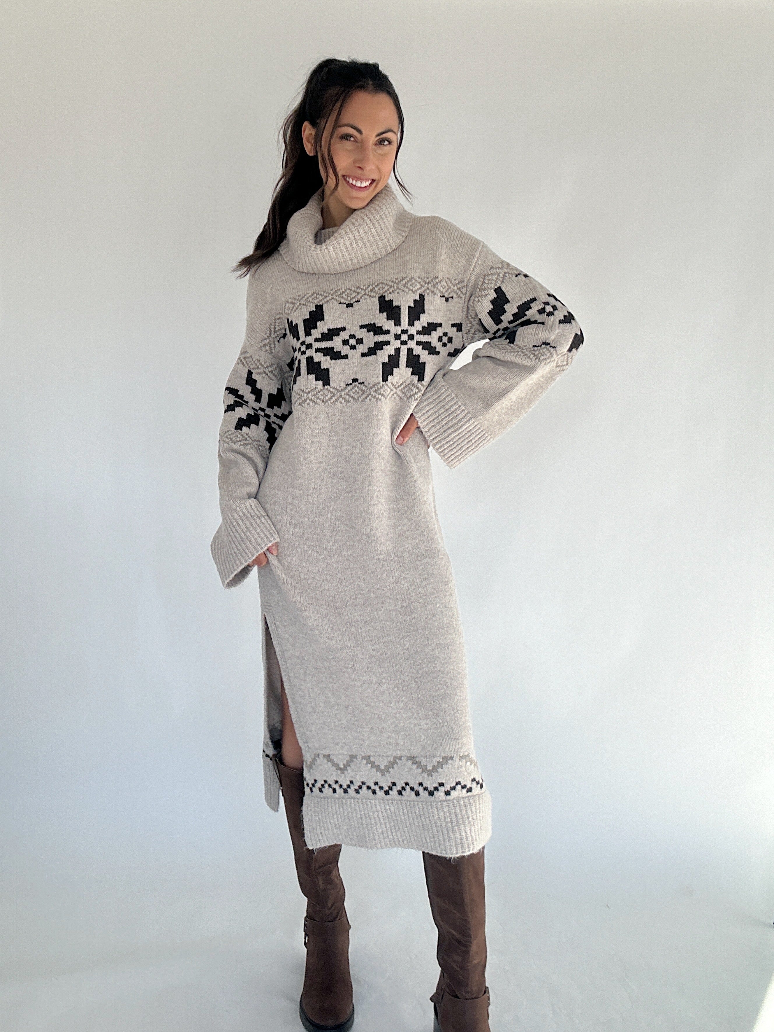 Woman wearing a long, patterned sweater dress with cowl neck against a white background