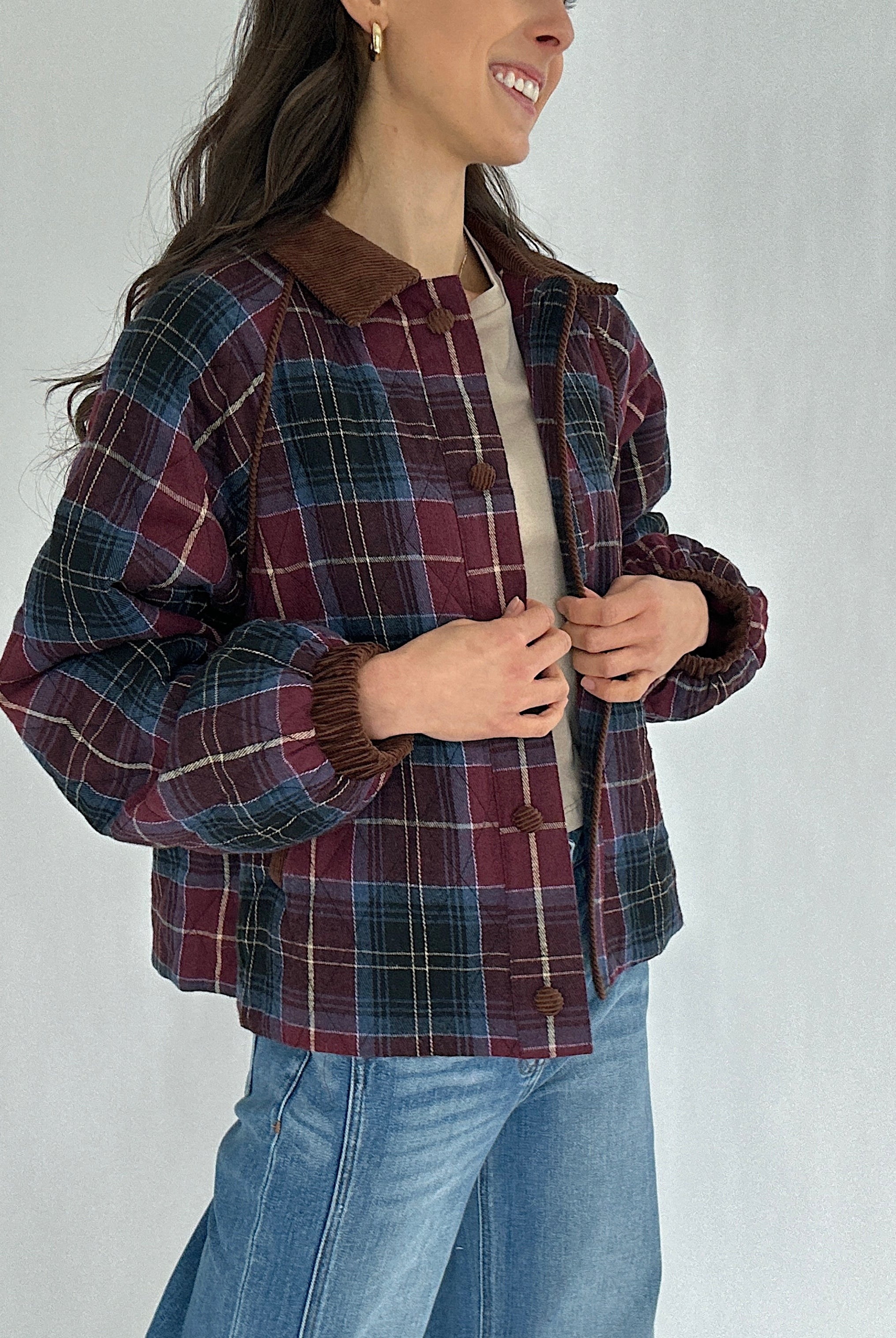 Person wearing a maroon plaid jacket with a plain background
