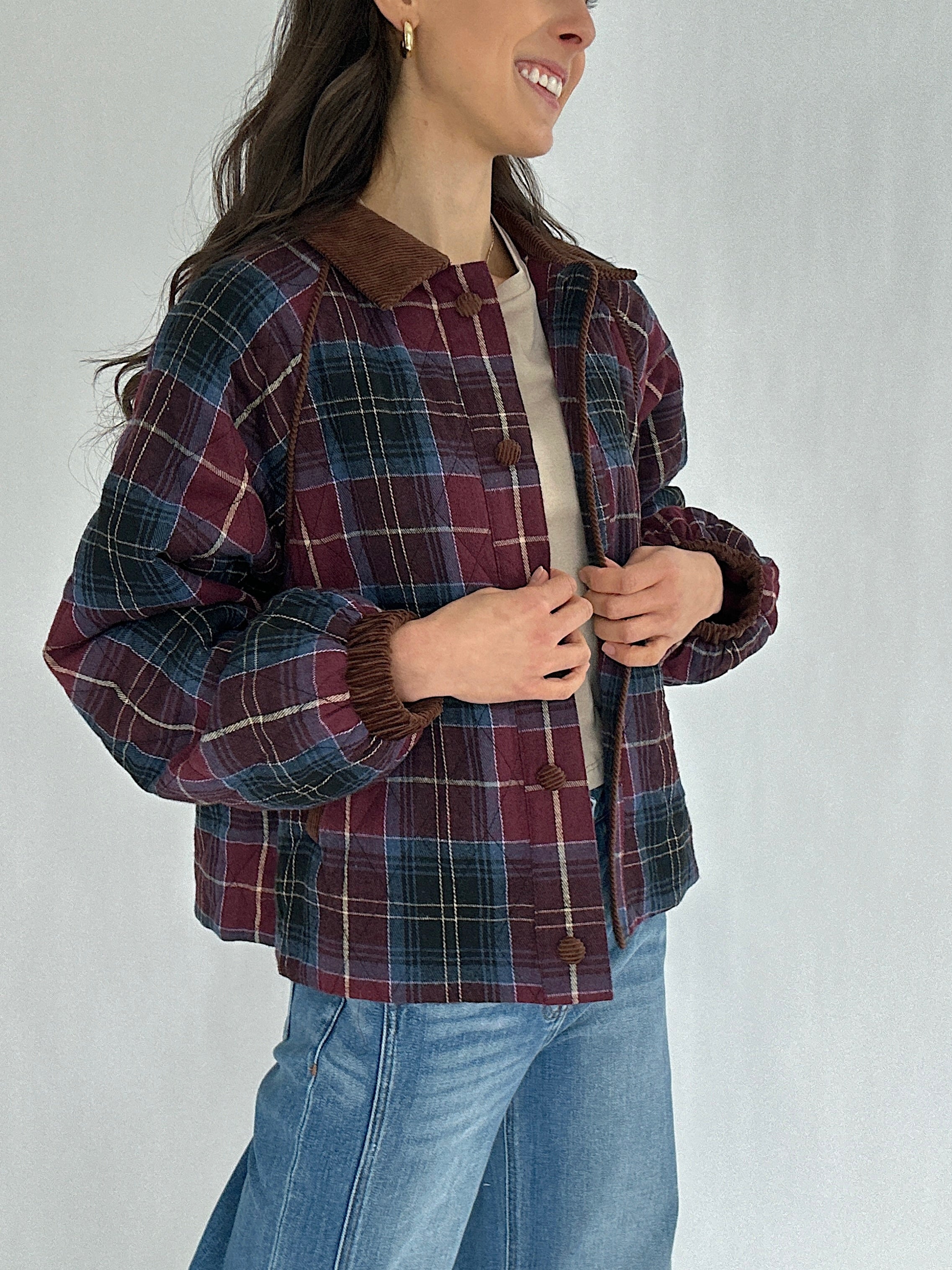 Person wearing a maroon plaid jacket with a plain background