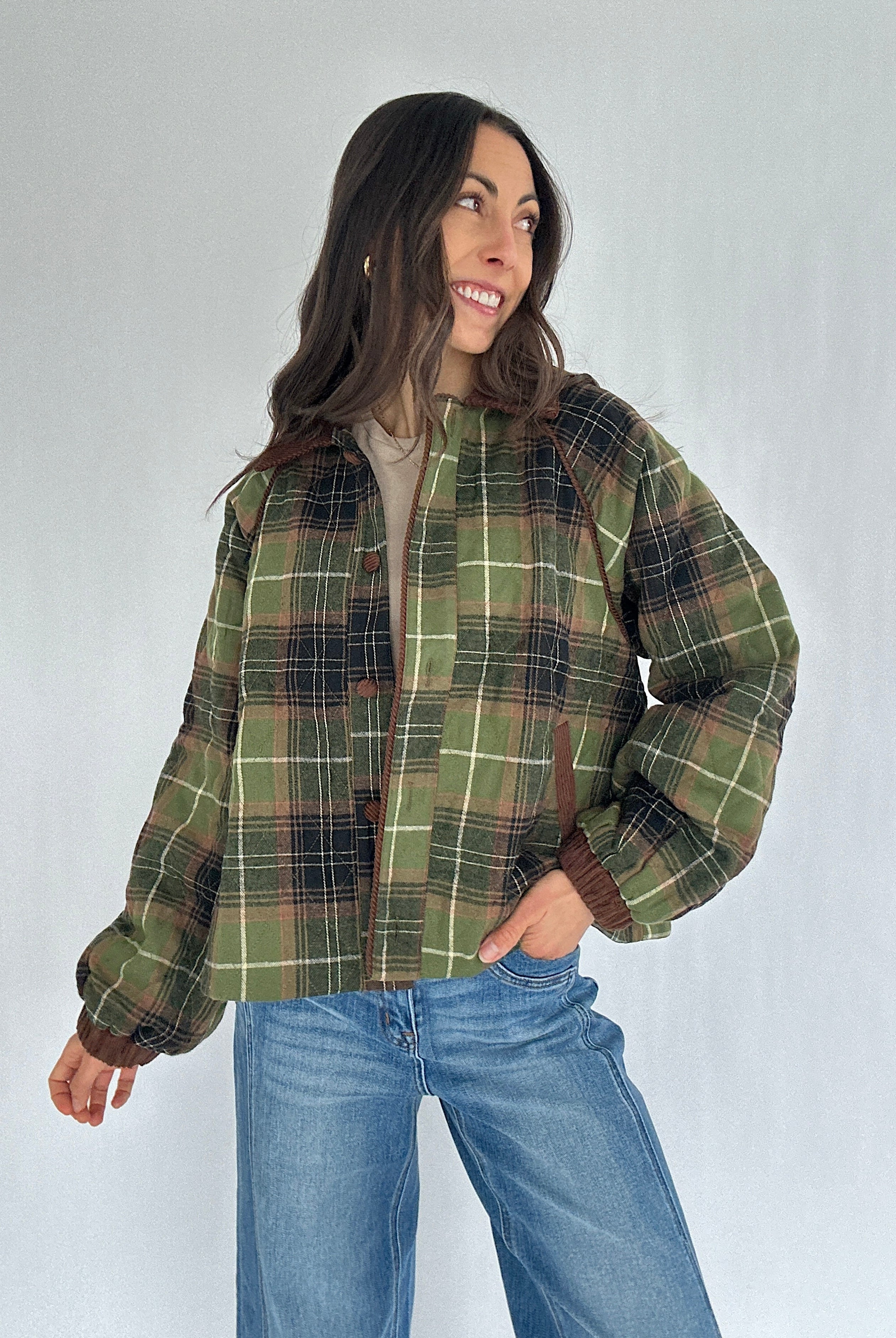 Person wearing a green plaid jacket and blue jeans against a white background