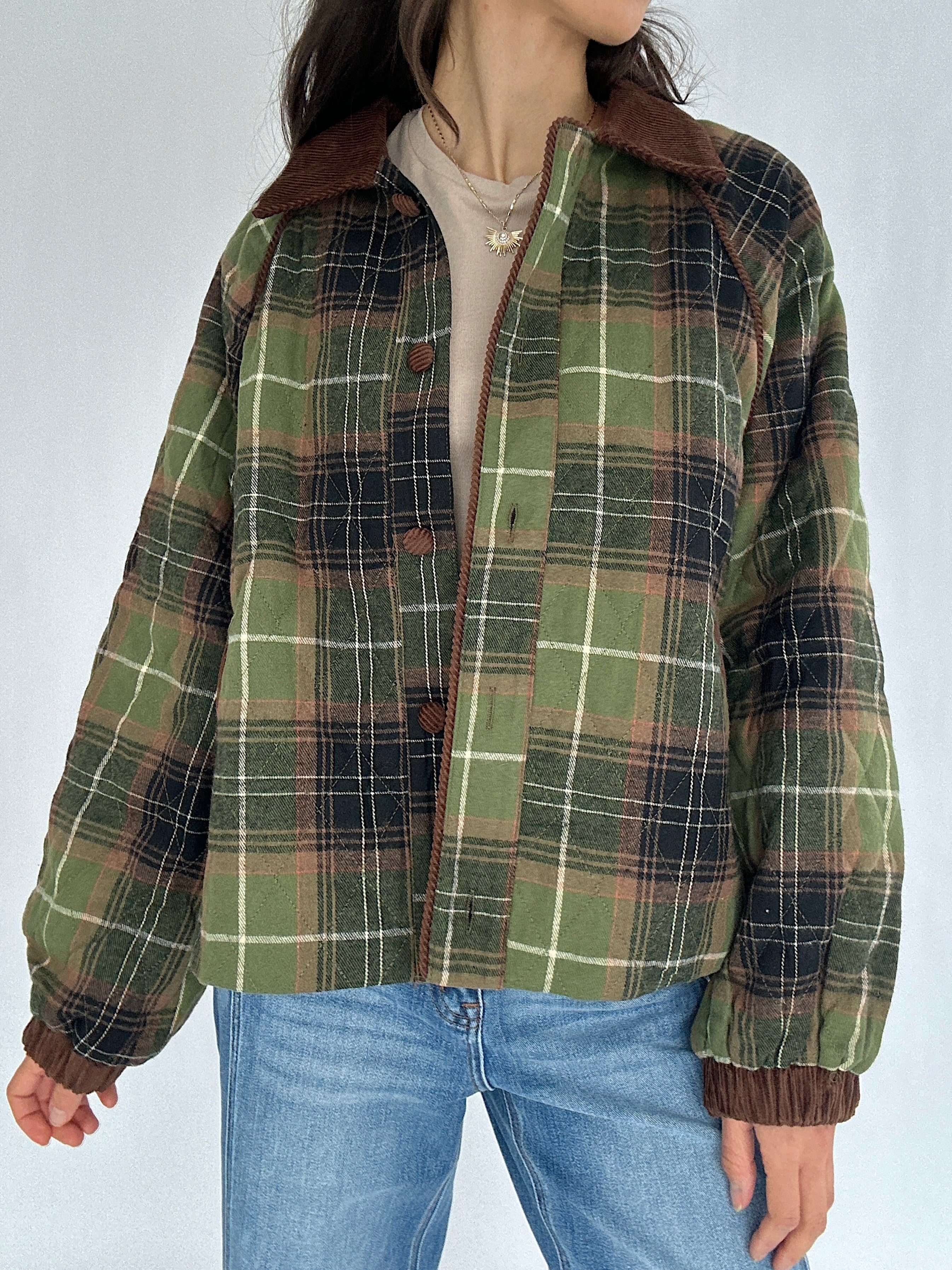 Person wearing a green plaid jacket with brown collar and cuffs on a white background