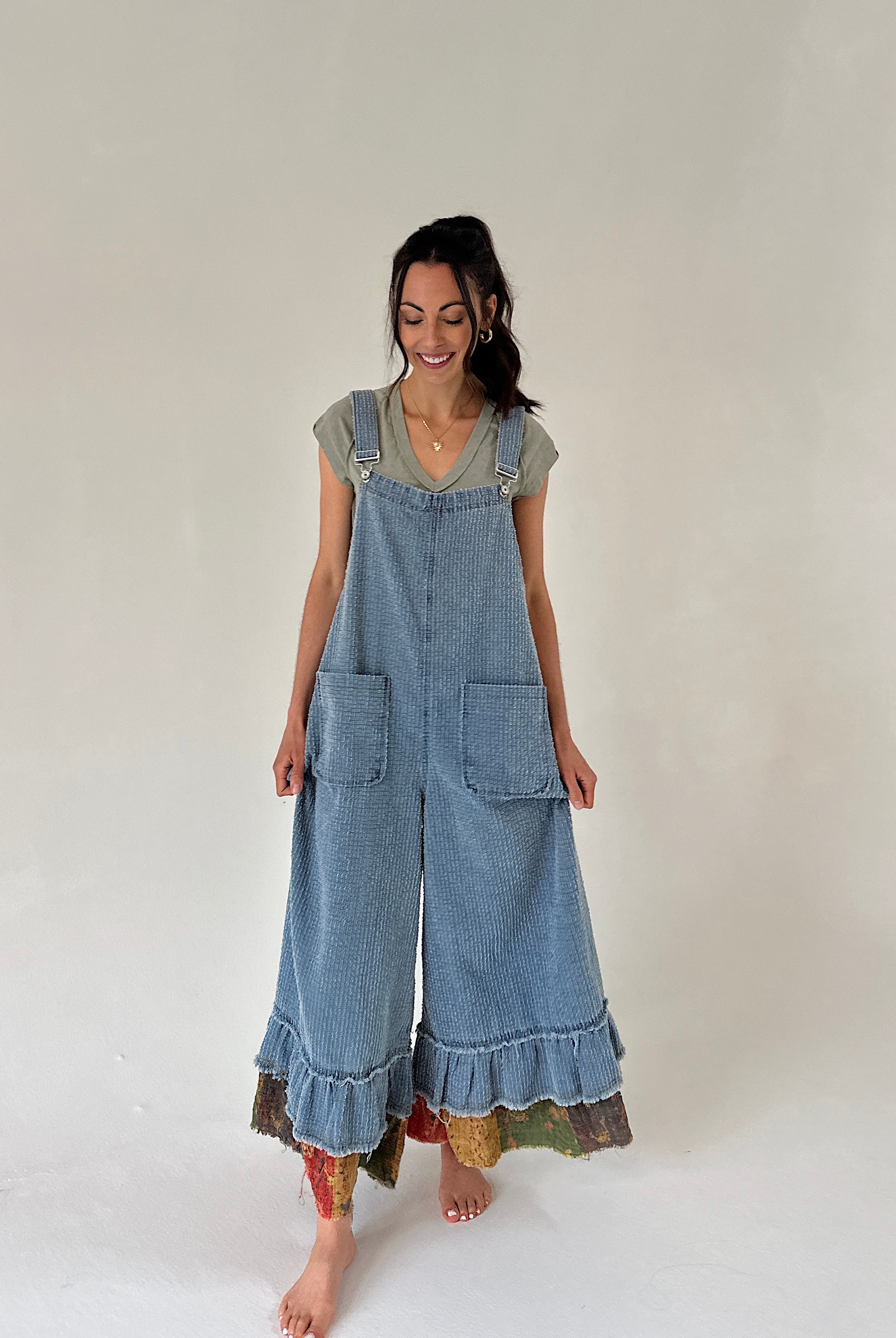 Woman wearing a denim overalls with ruffled hem on a plain background