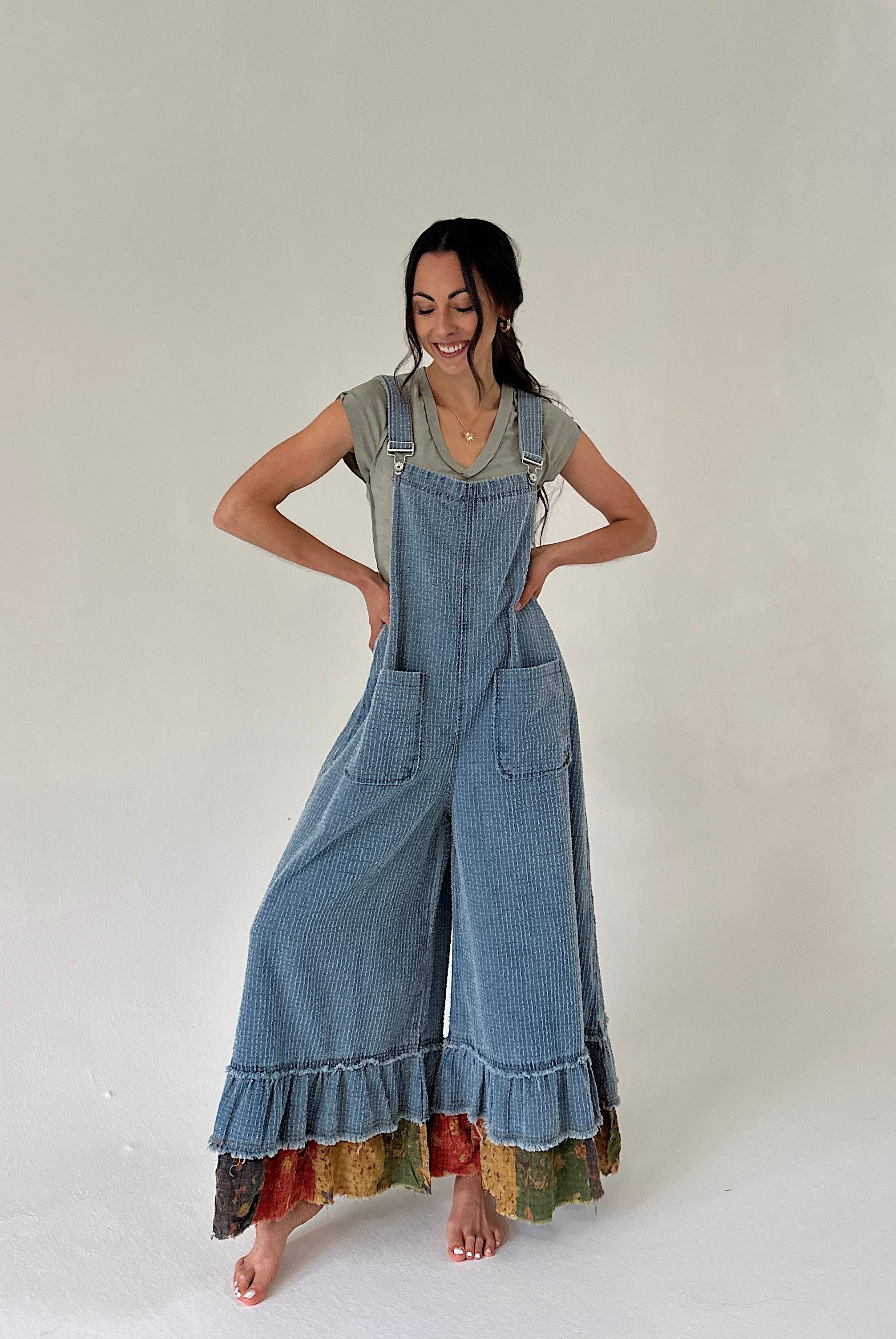 Woman wearing a long denim overalls with colorful hem on a white background