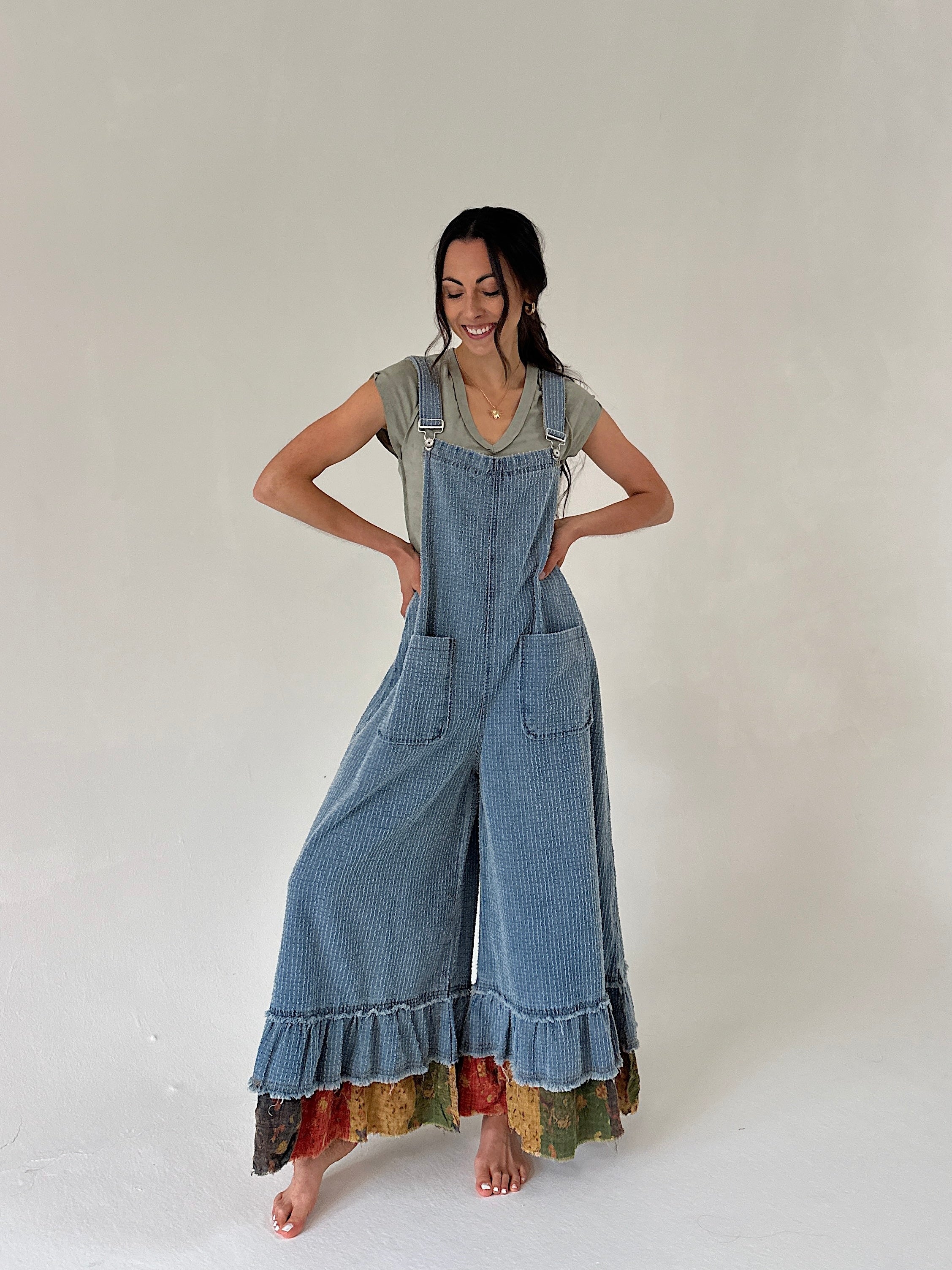 Woman wearing a long denim overalls with colorful hem on a white background