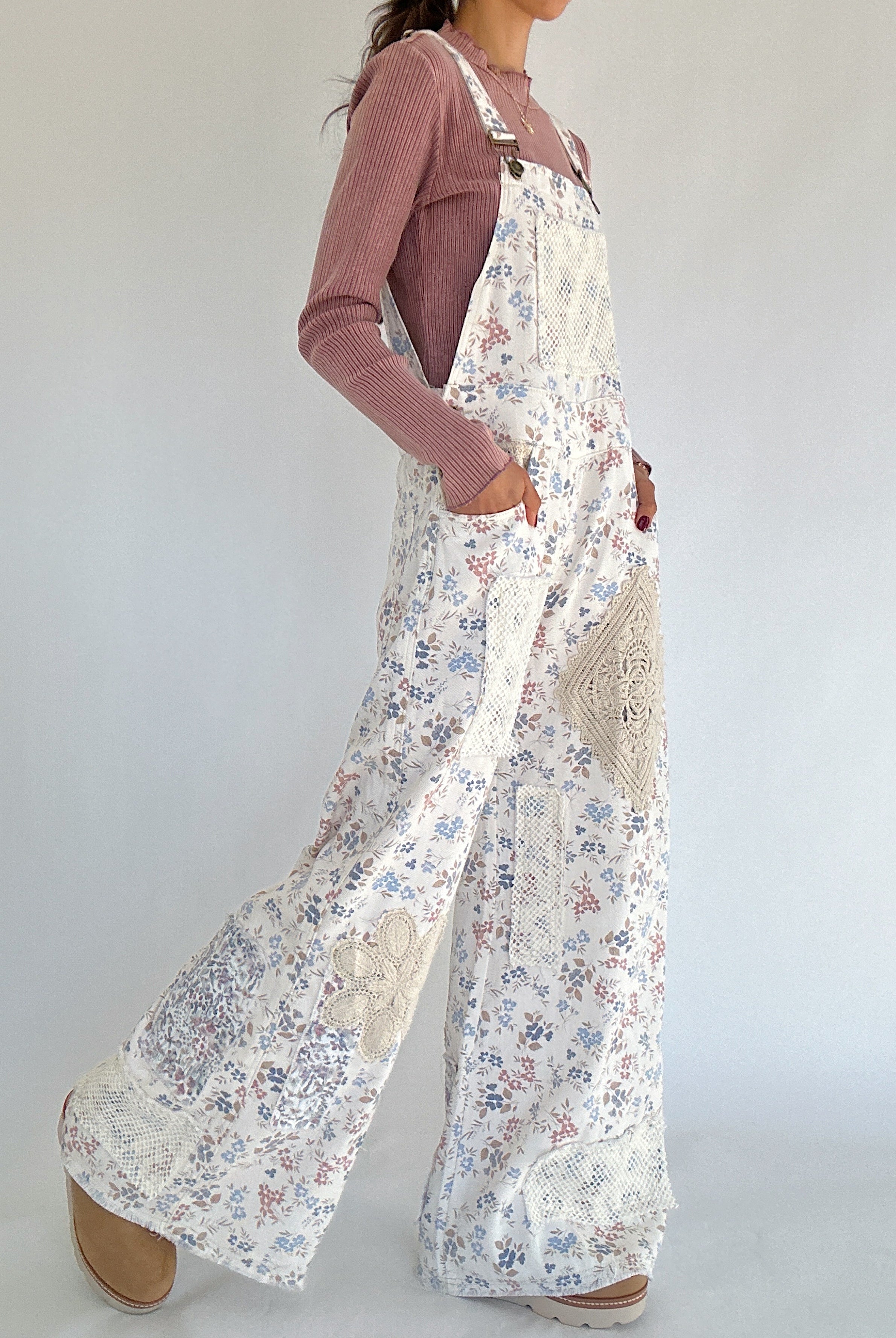Person wearing a floral overalls with a plain background side view