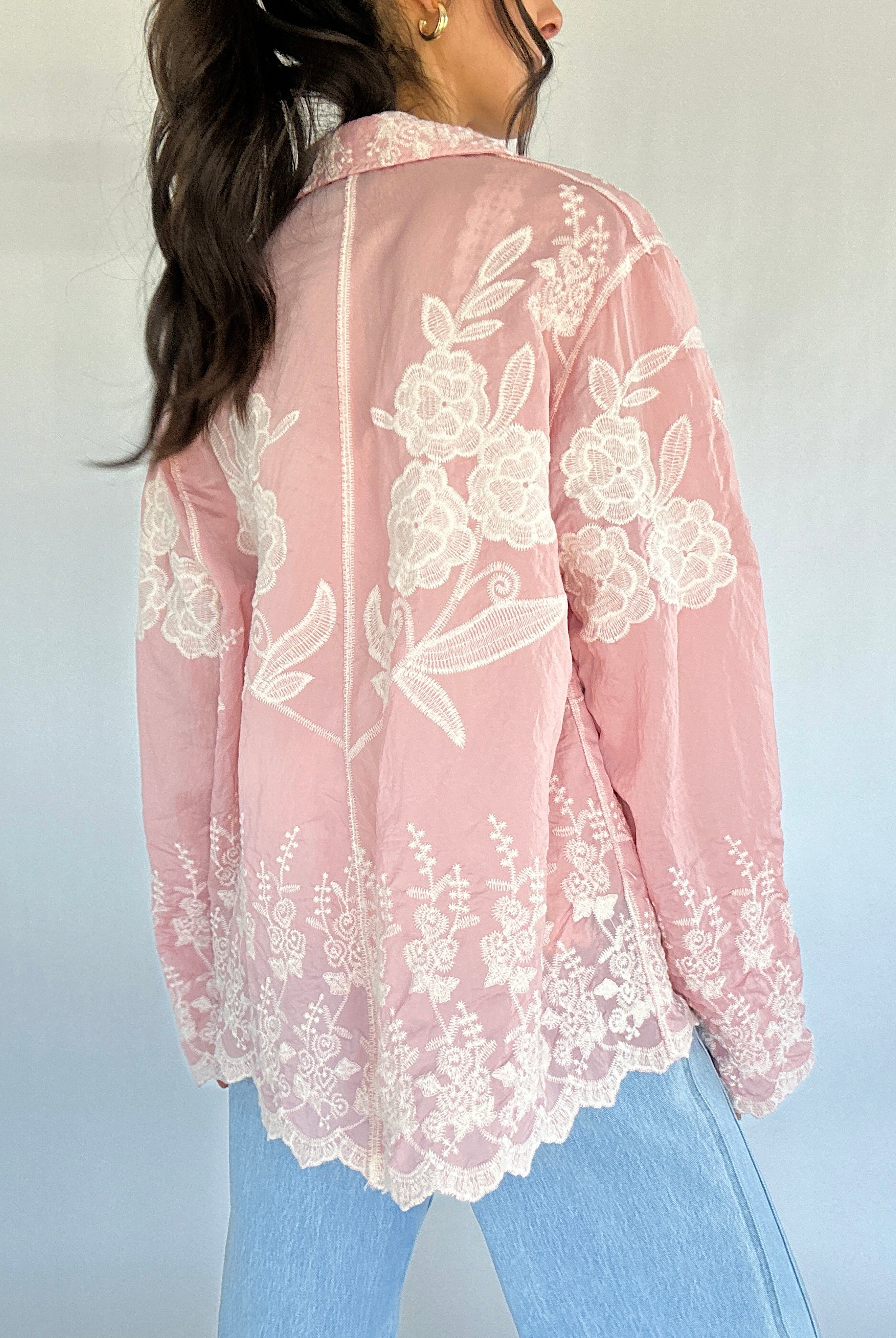 Pink lace top worn by a person with a blurred background showing back