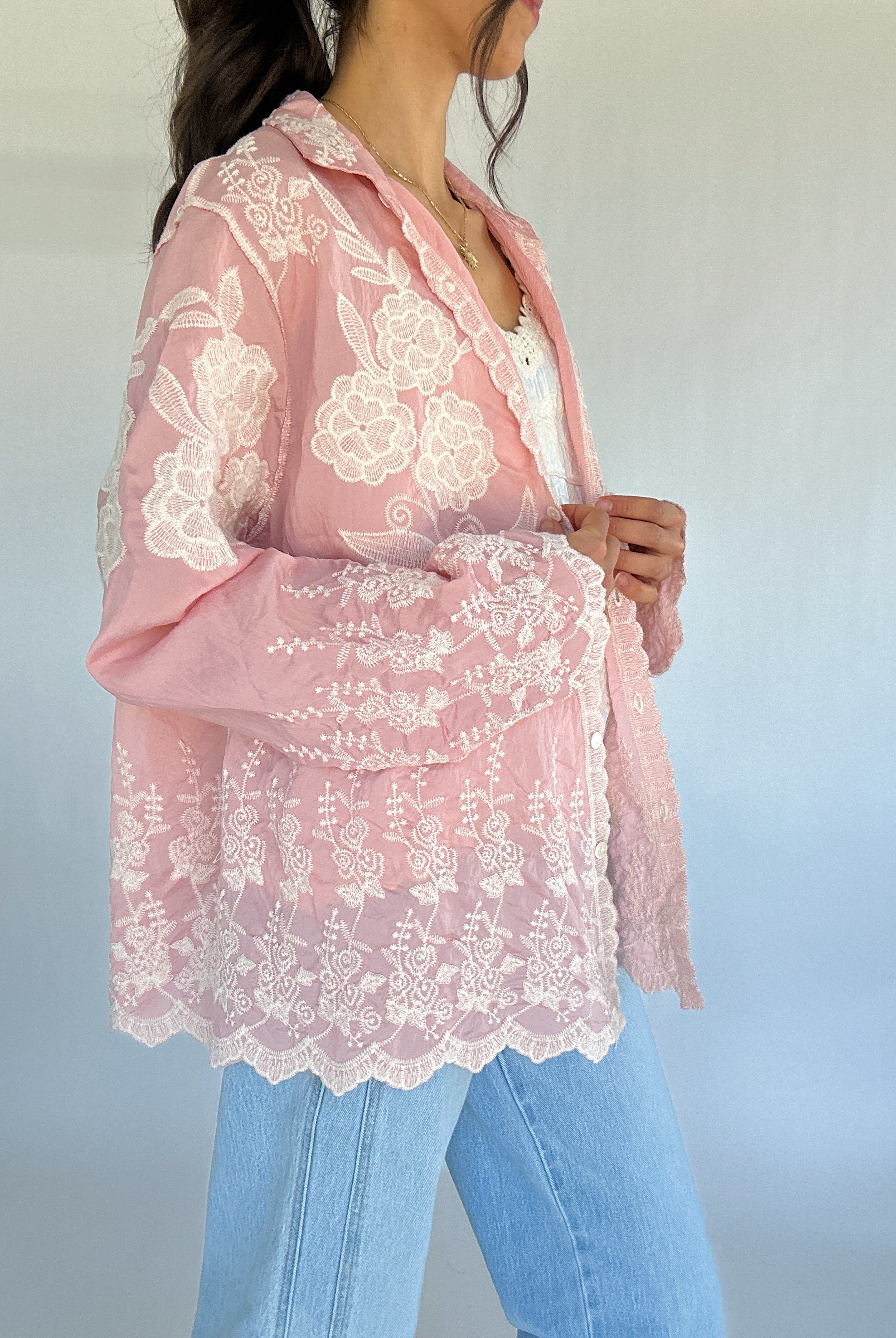 Pink lace blouse worn by a person with a blurred background showing side