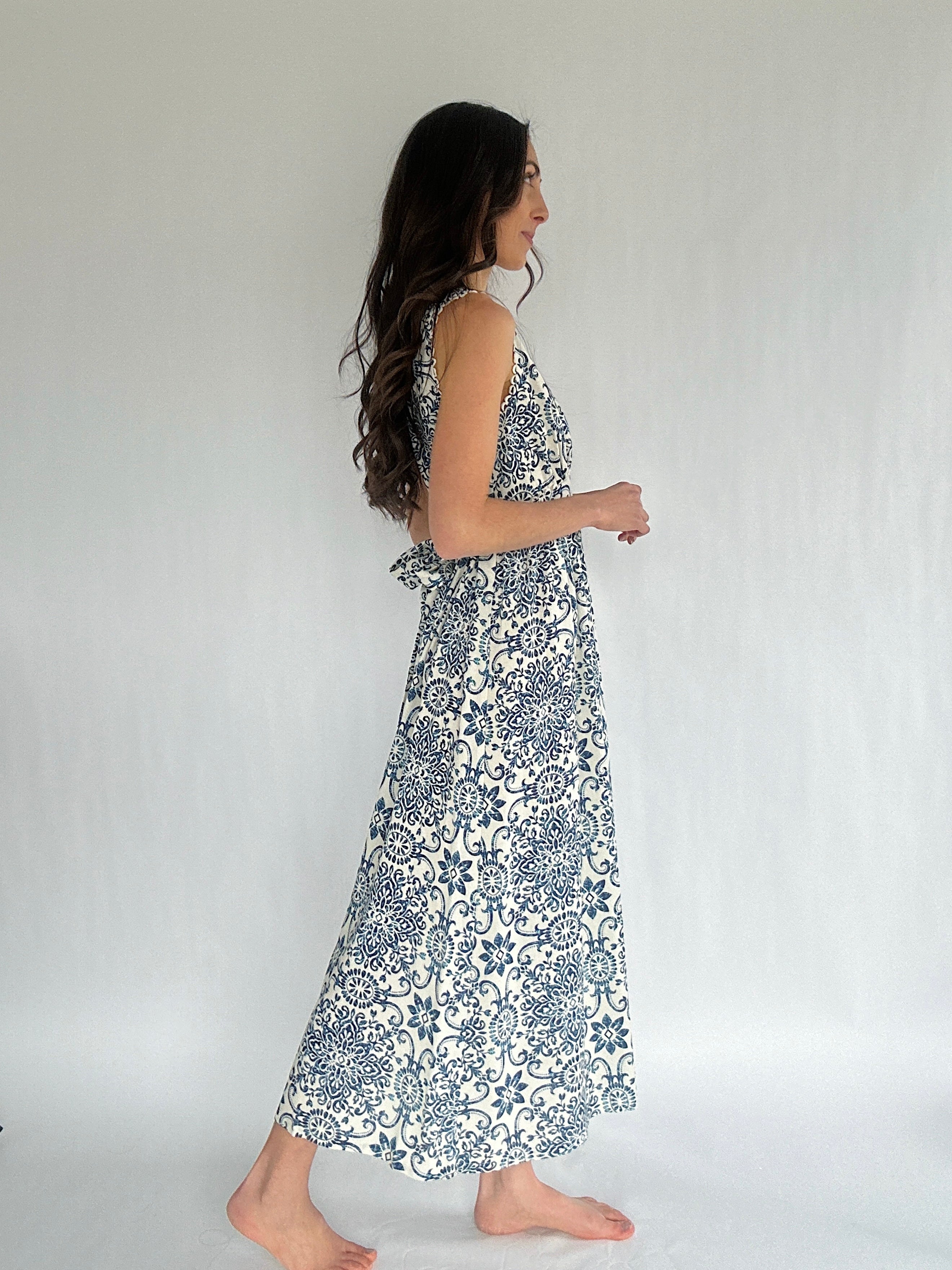 Woman wearing a floral dress against a plain background from side