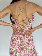 Back view of a floral dress with criss-cross straps on a plain background