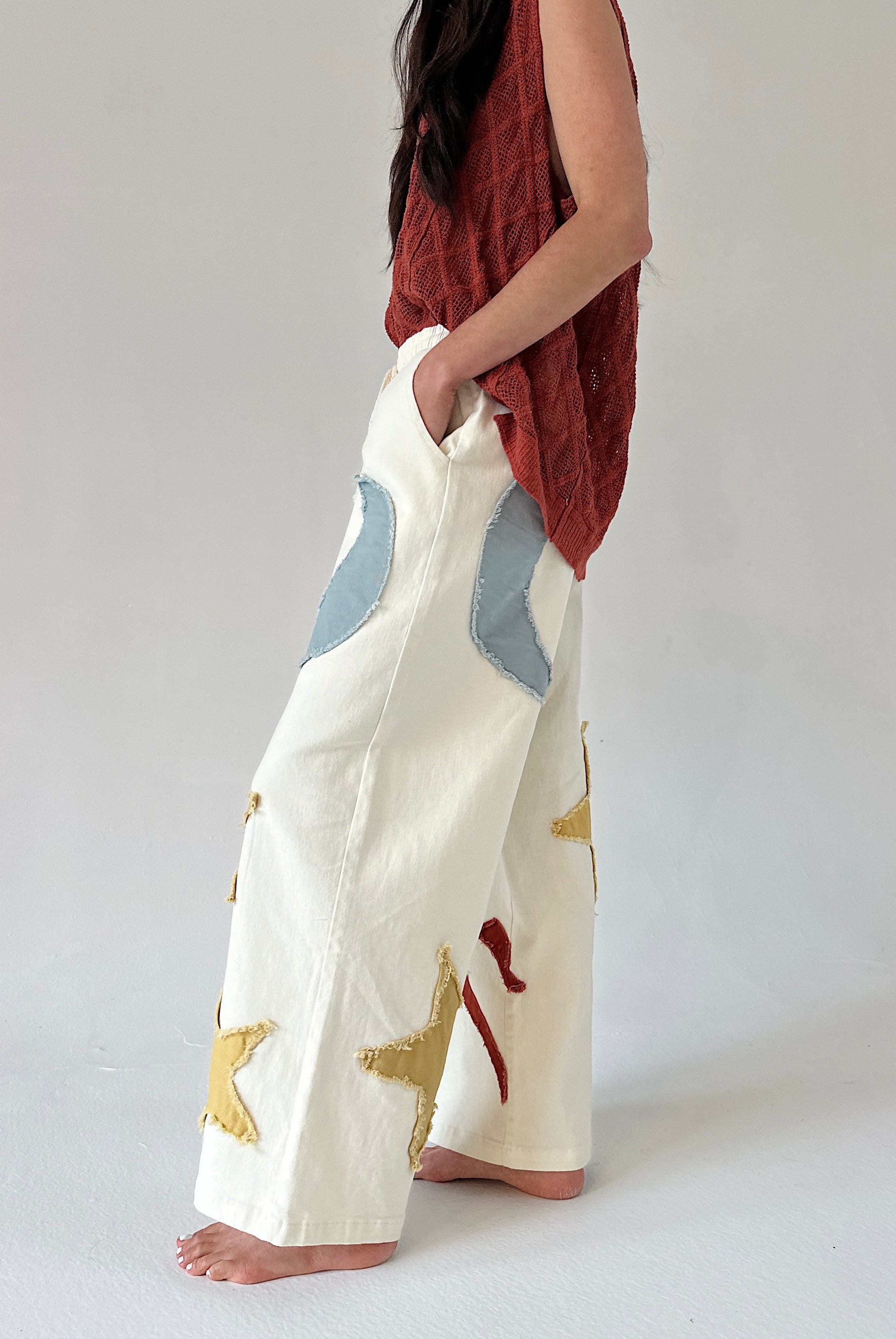 Person wearing white pants with blue and gold abstract patterns on a plain background