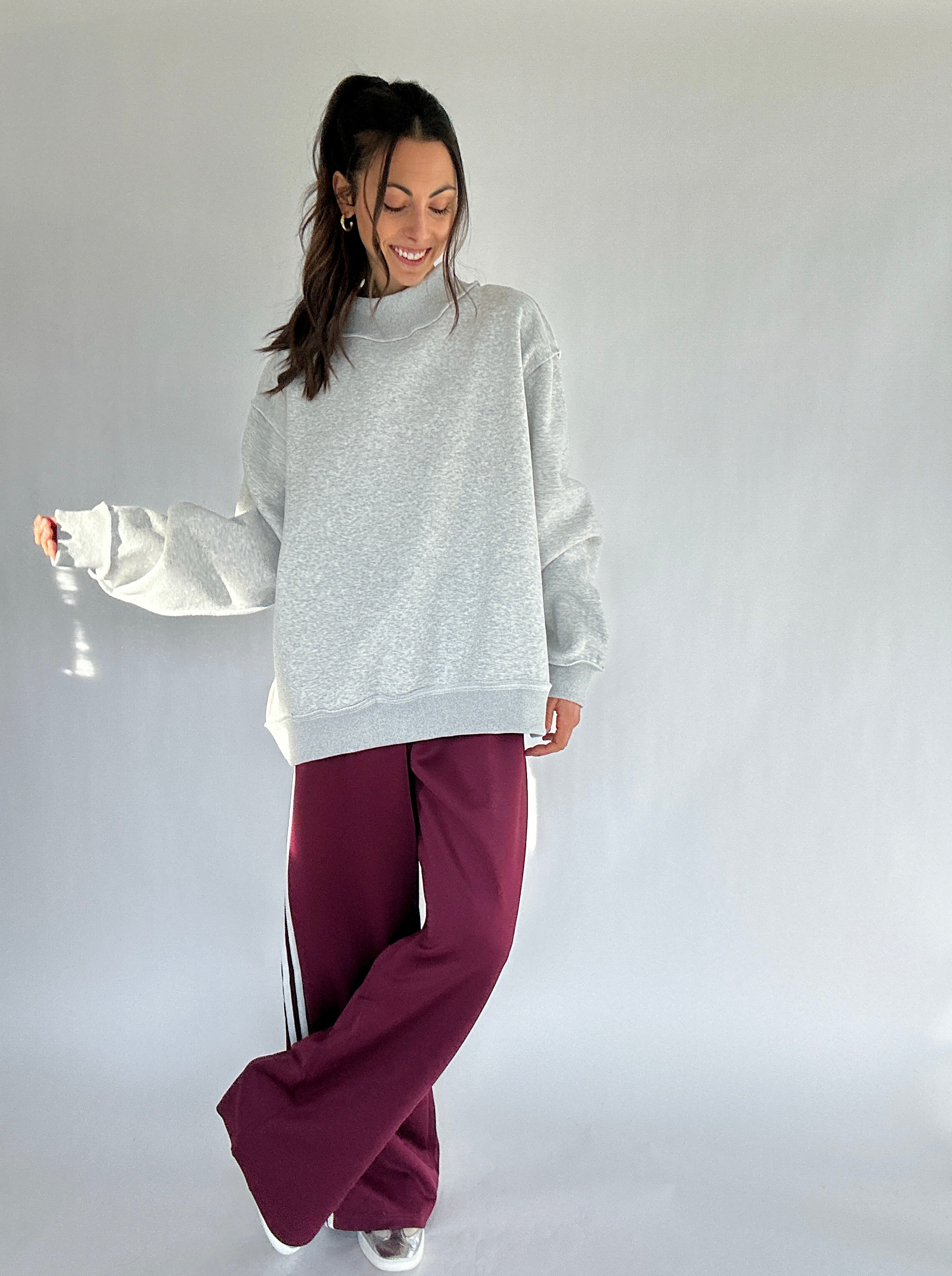 Woman wearing a gray sweatshirt and burgundy pants on a white background