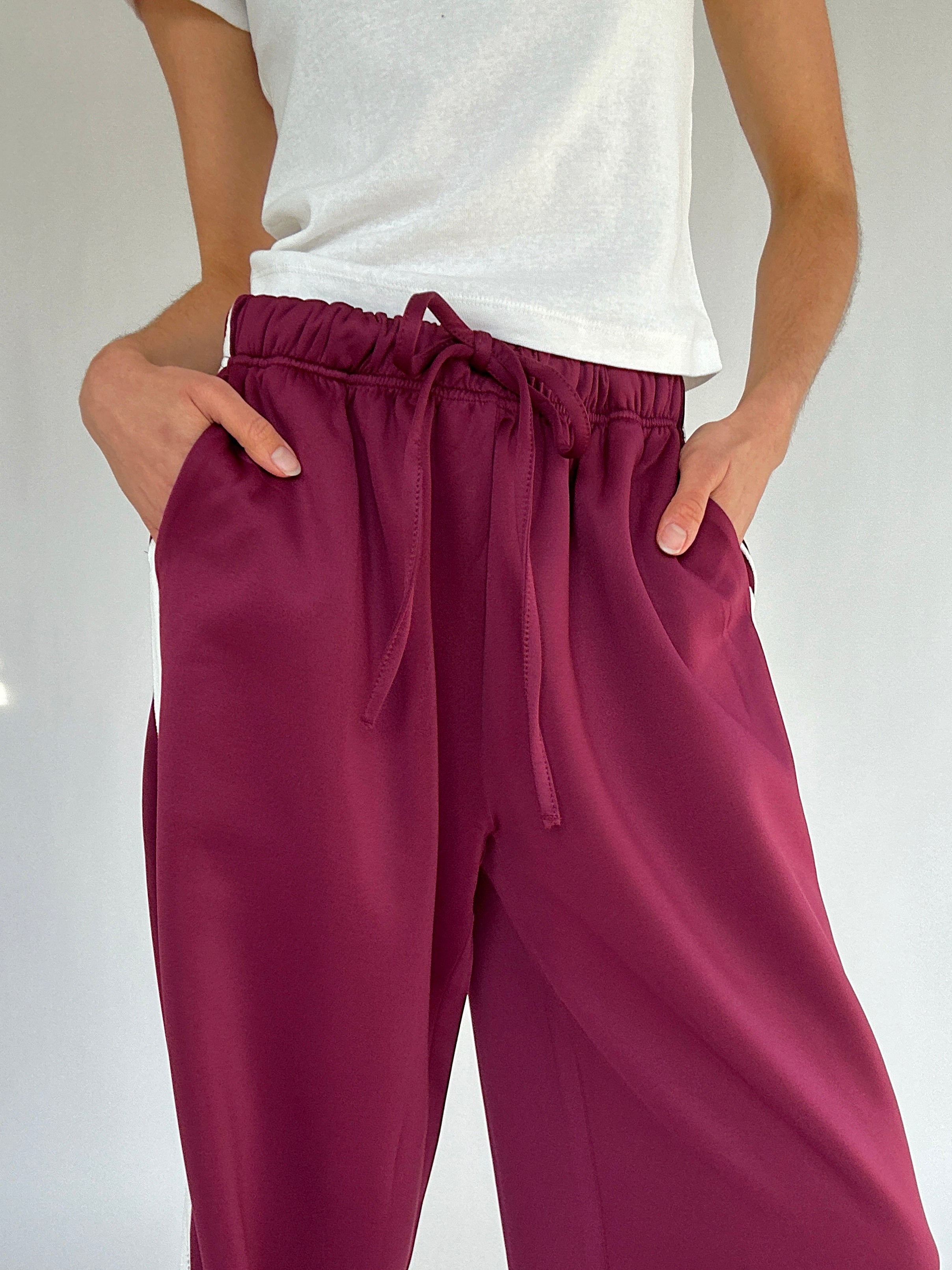 Maroon pants with a drawstring waist worn by a person on a white background