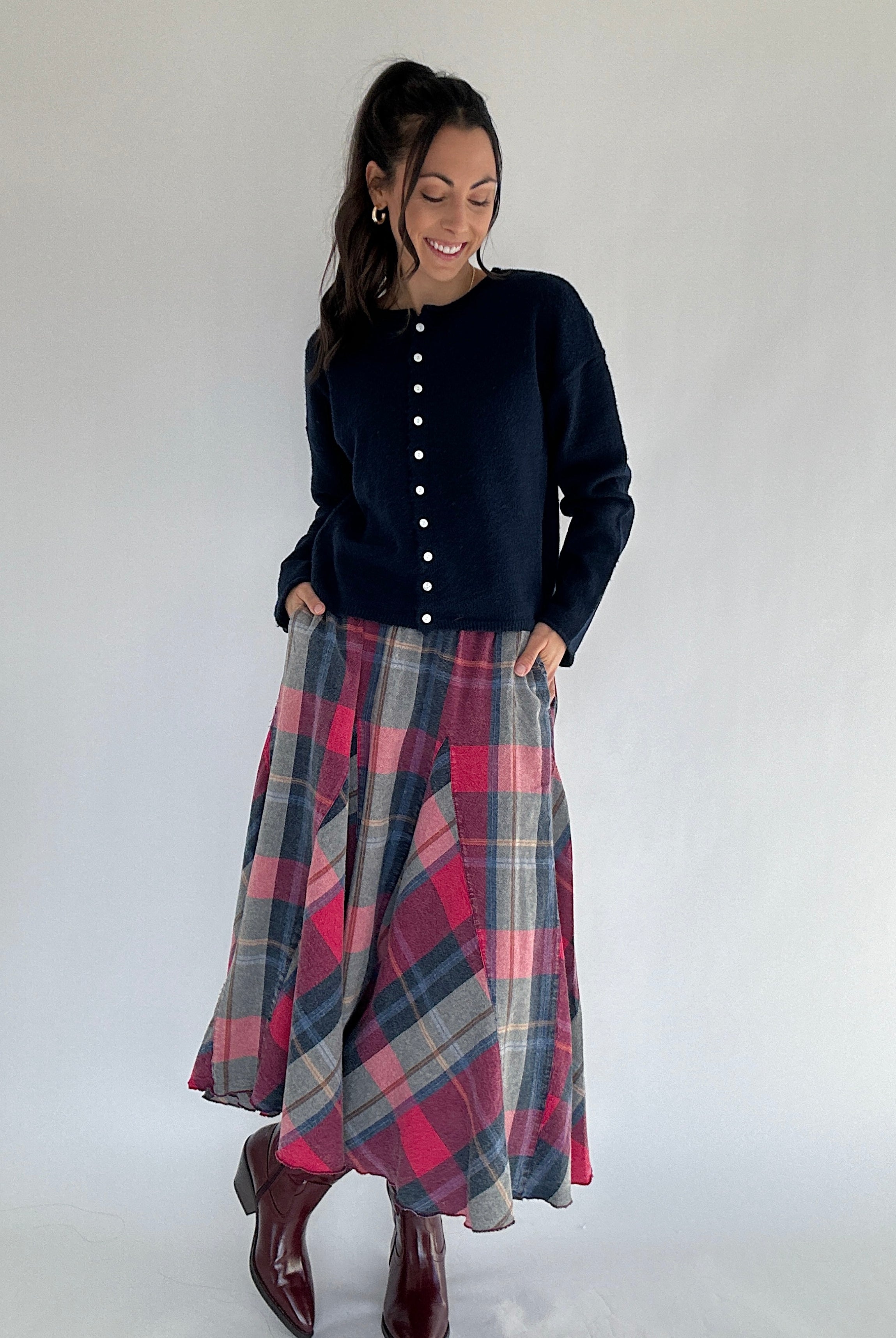 Woman wearing a navy cardigan sweater and plaid skirt on a white background