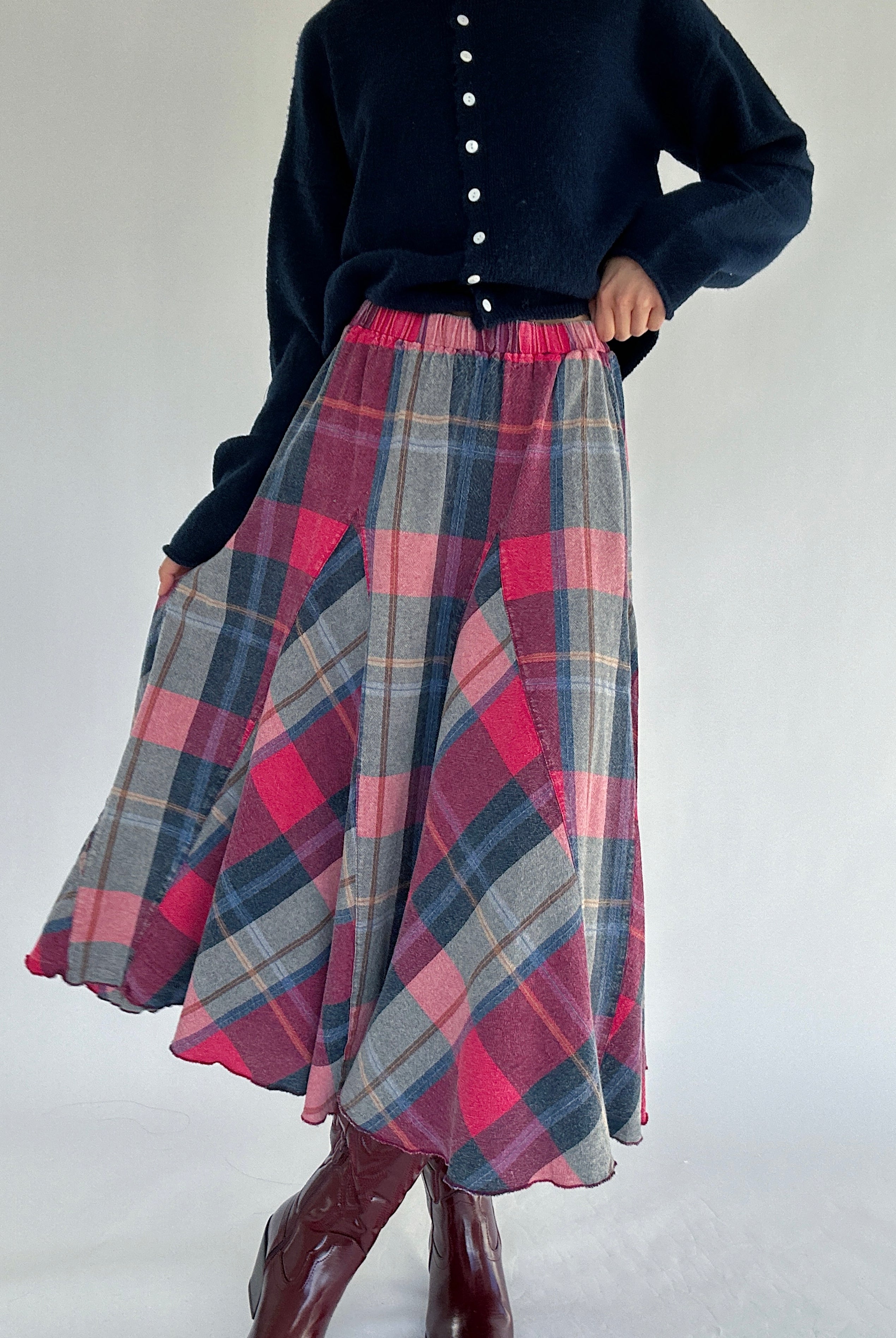Person wearing a navy sweater and plaid skirt on a white background
