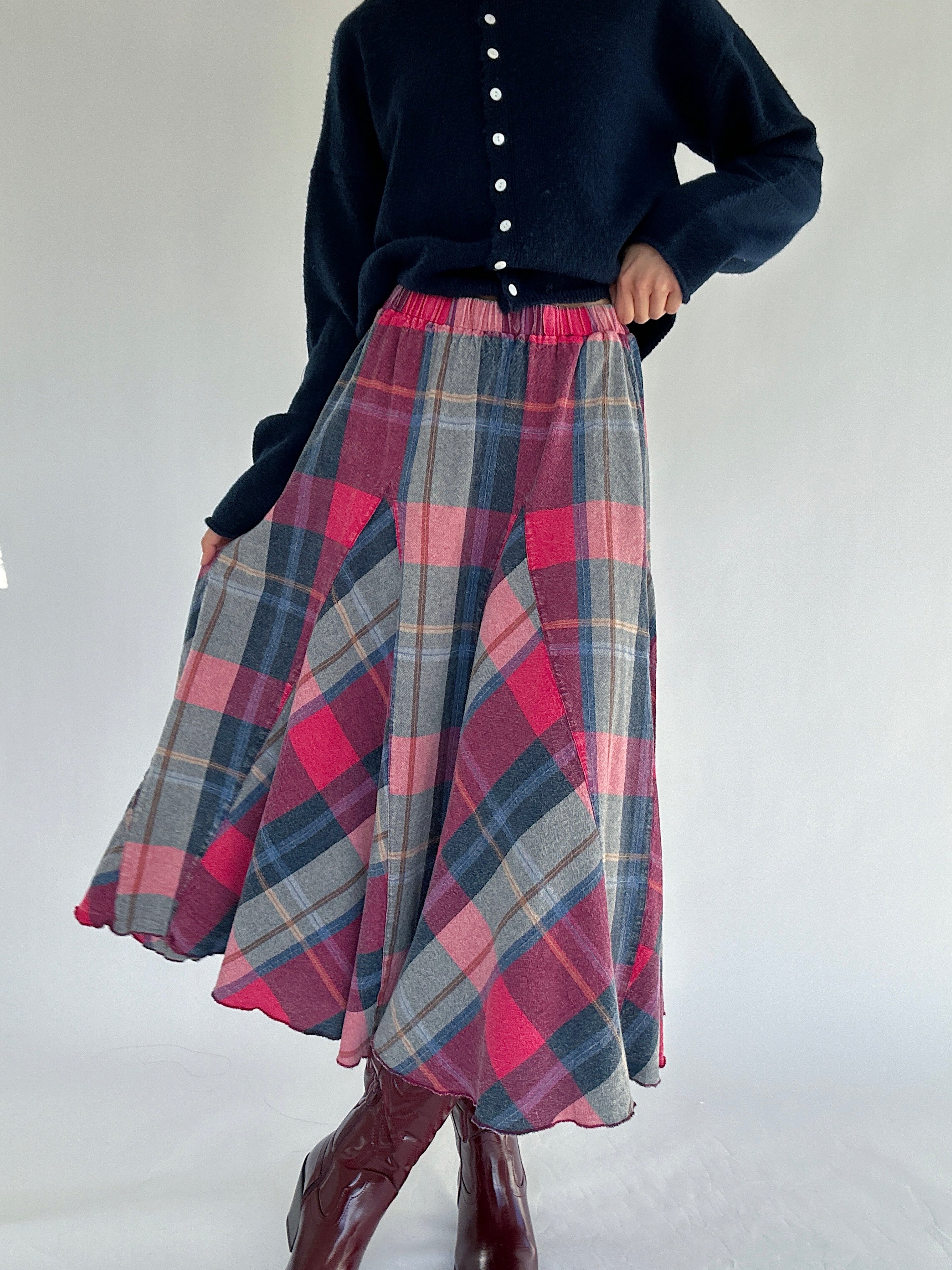 Person wearing a navy sweater and plaid skirt on a white background