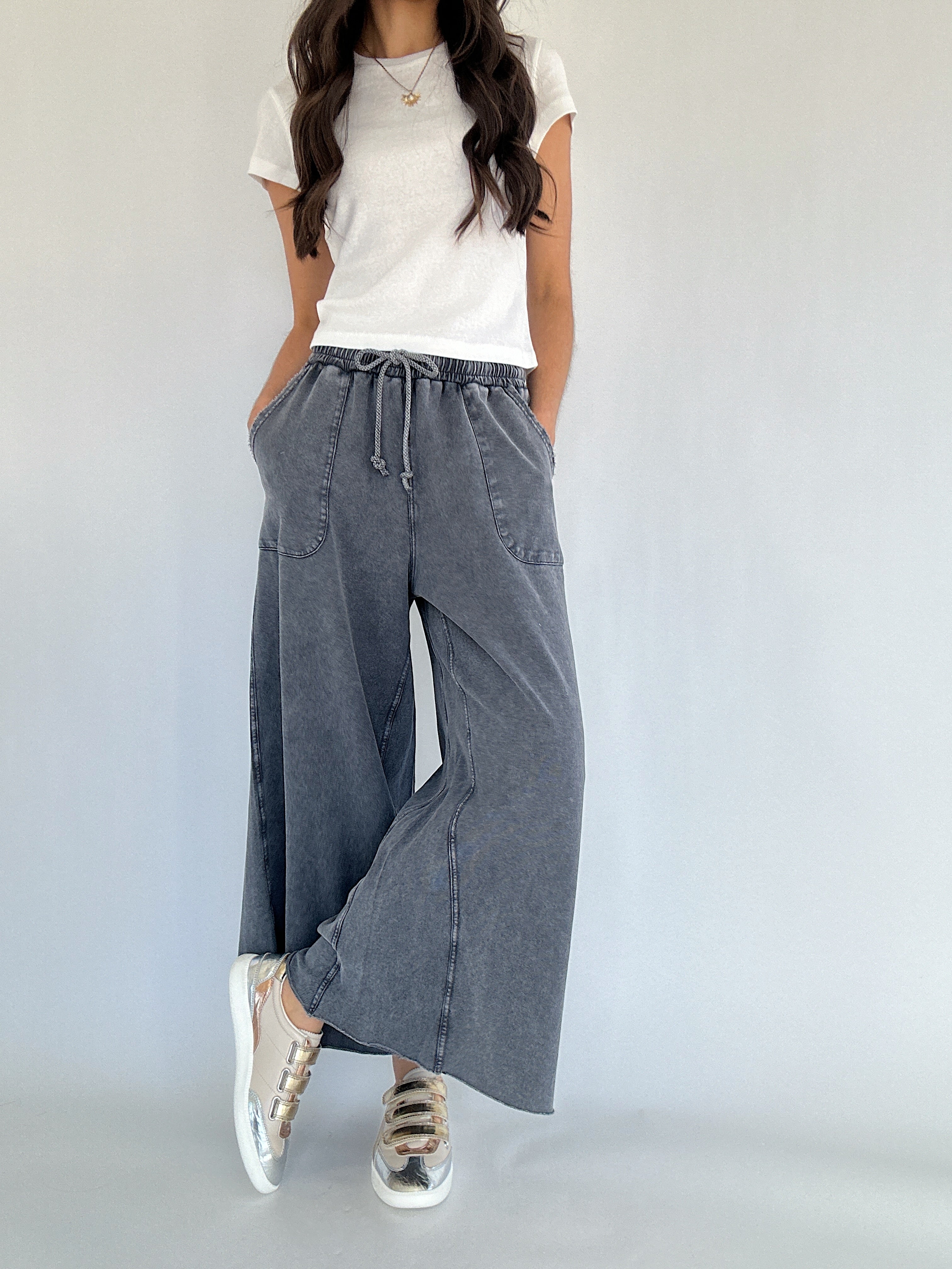 Person wearing a white t-shirt and gray wide-leg pants against a plain background